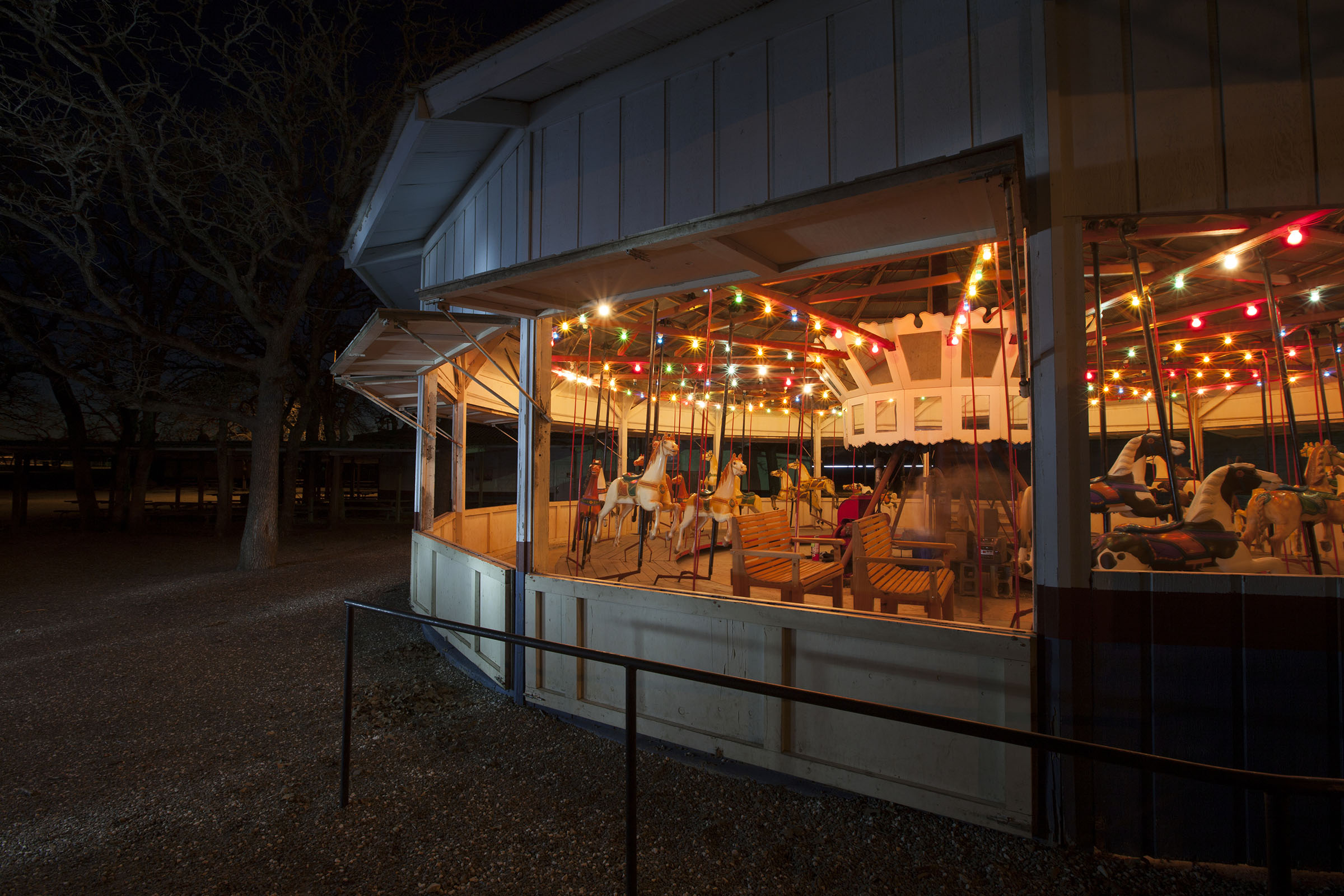 The exterior of a wooden carousel with bright colorful lights inside