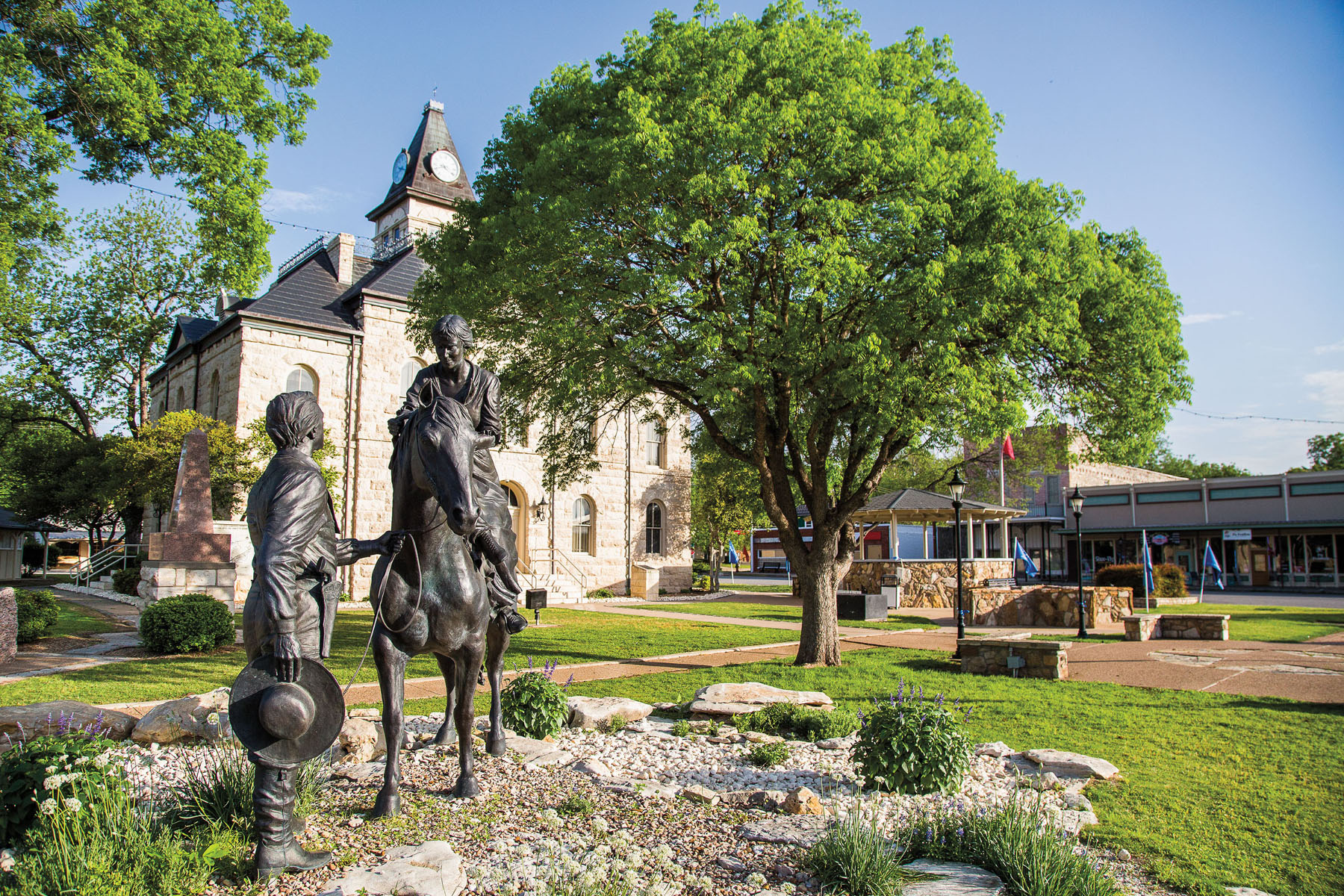 Two dark bronze statues in a green yard in front of a stone courthouse