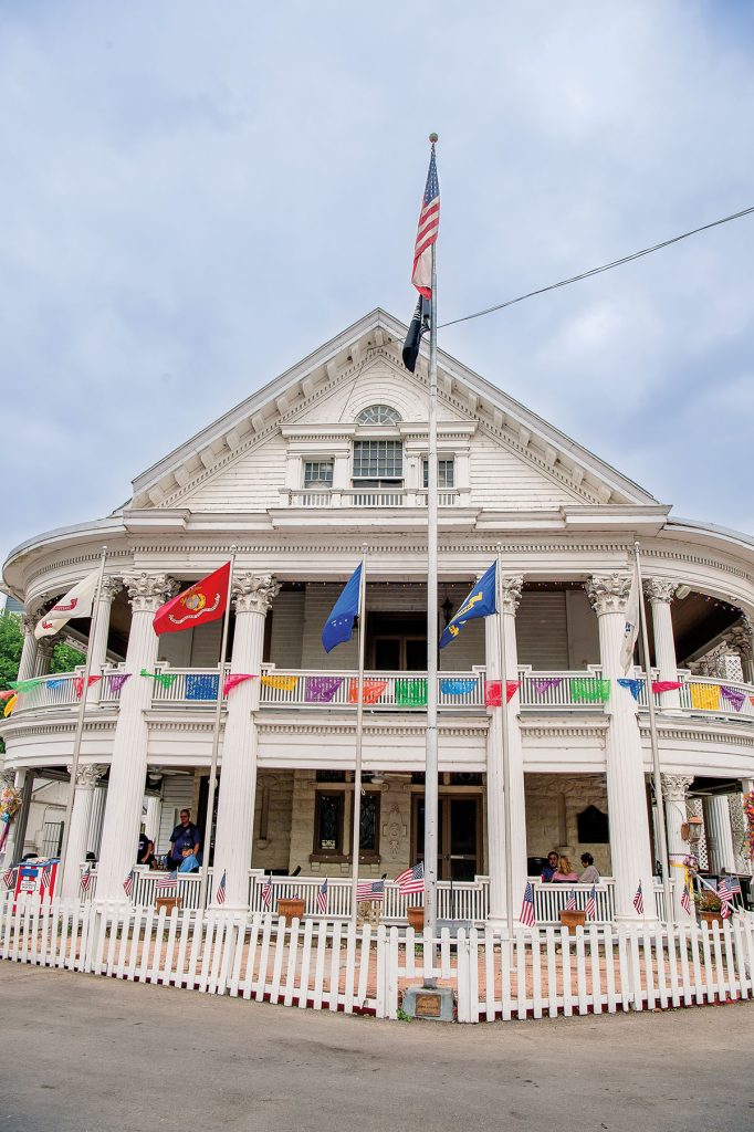 The exterior of a white building displaying numerous flags in bright colors