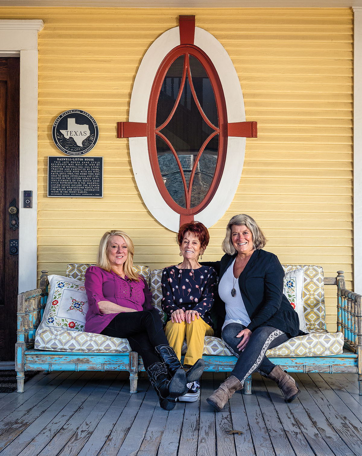 Three women sit underneath a window next to a Texas State Historical Marker