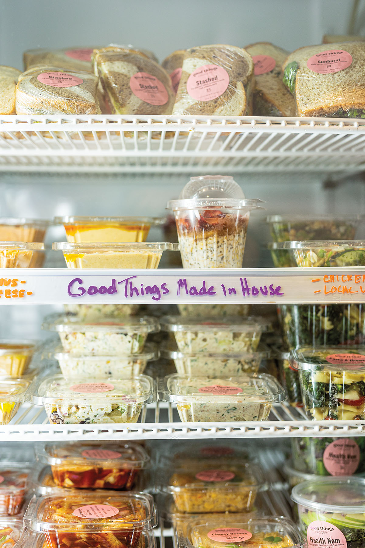 A cooler of plastic containers labeled in sharpie reading "Good Things Made in House"