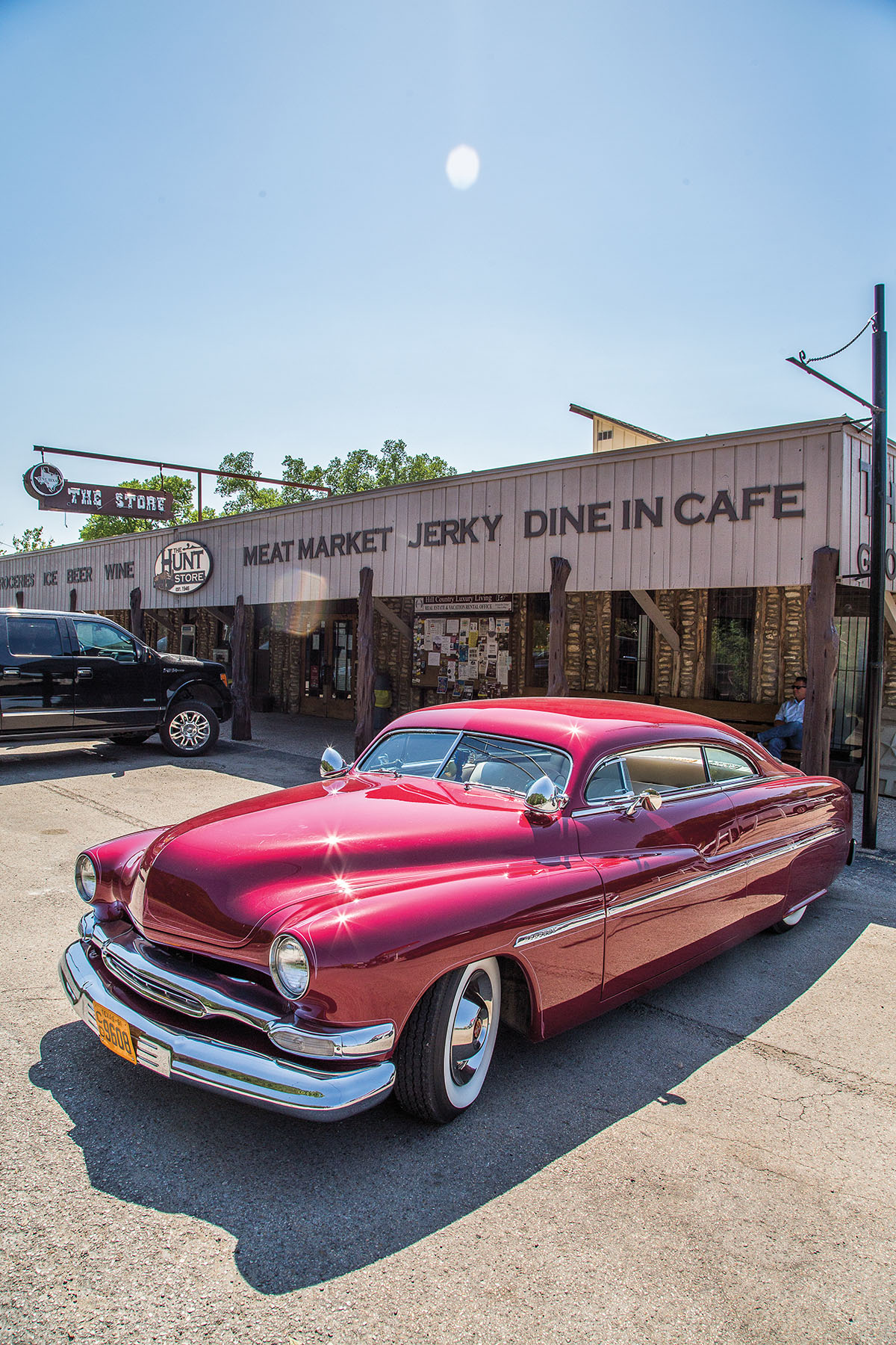 A red vintage car parked in front of the exterior of a storefront