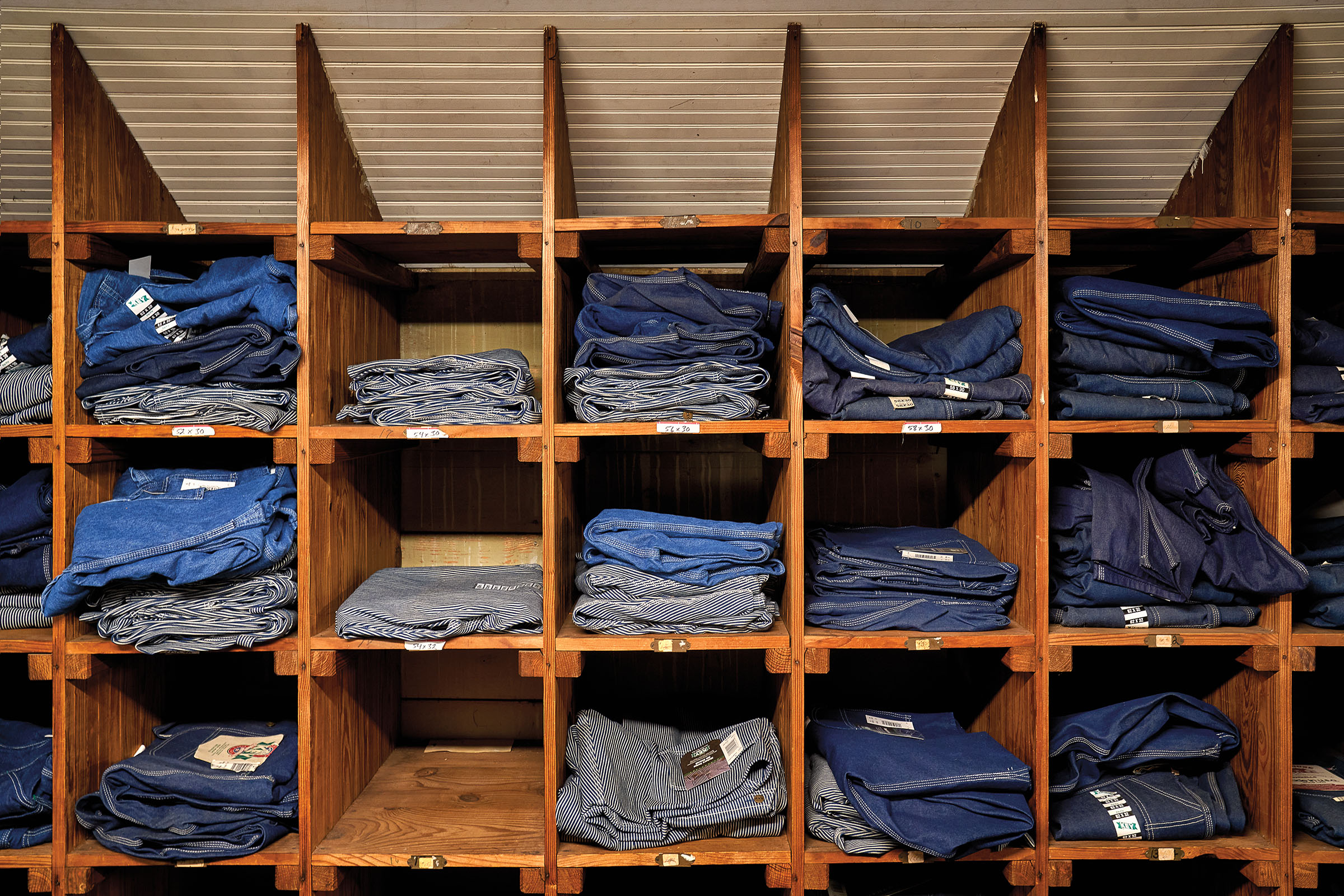 Various washes of denim clothing neatly stacked in wooden cubbies