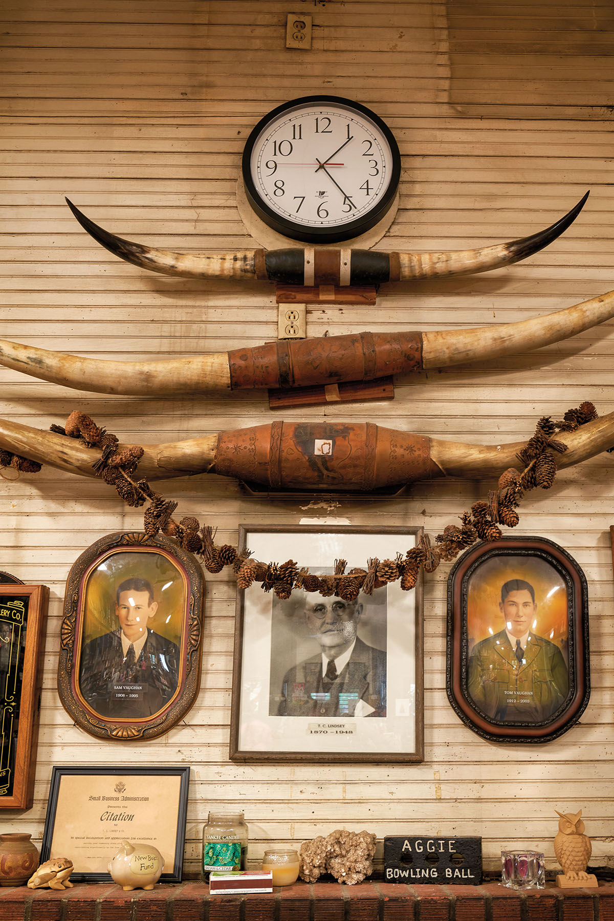 Cow horns, a clock, and vintage photographs adorn a wood-paneled wall