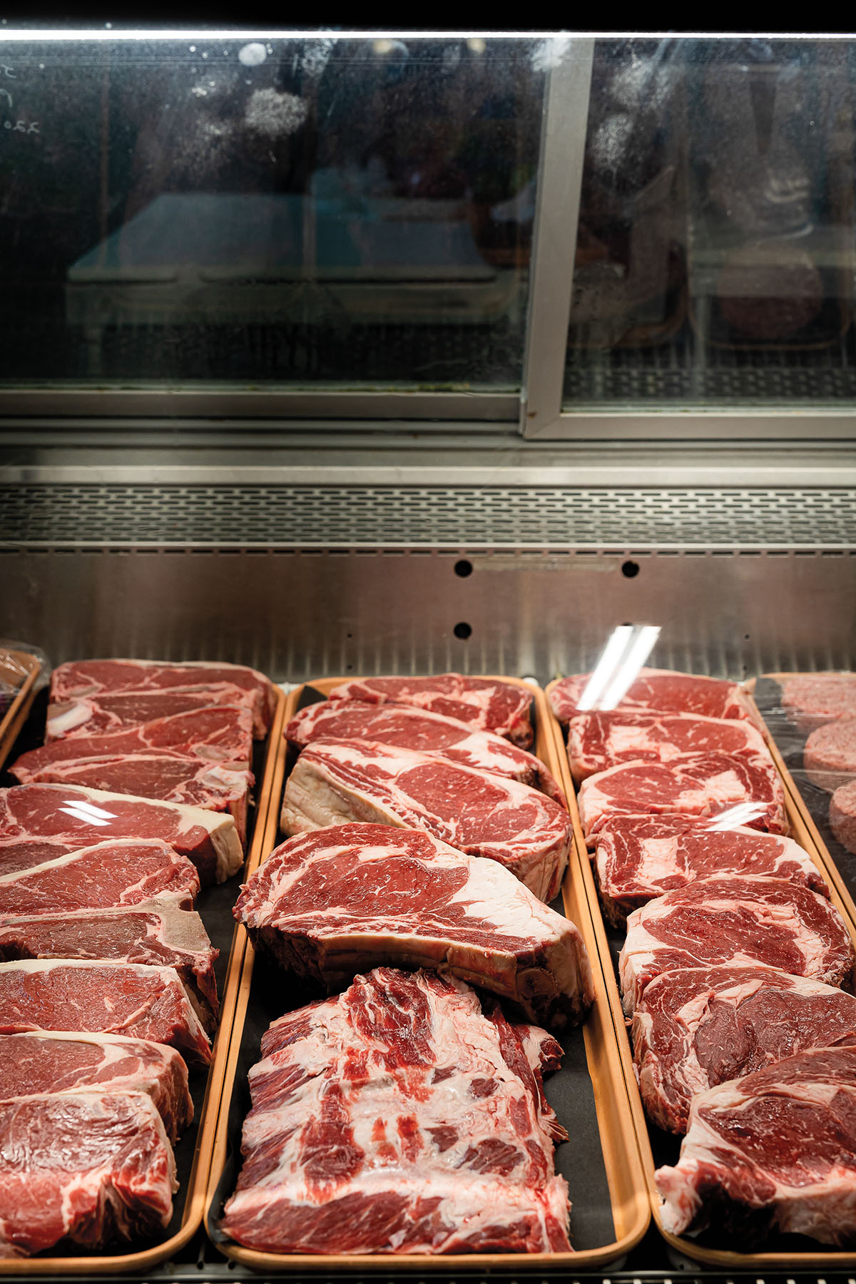 Large pieces of beef inside of a cooler display case