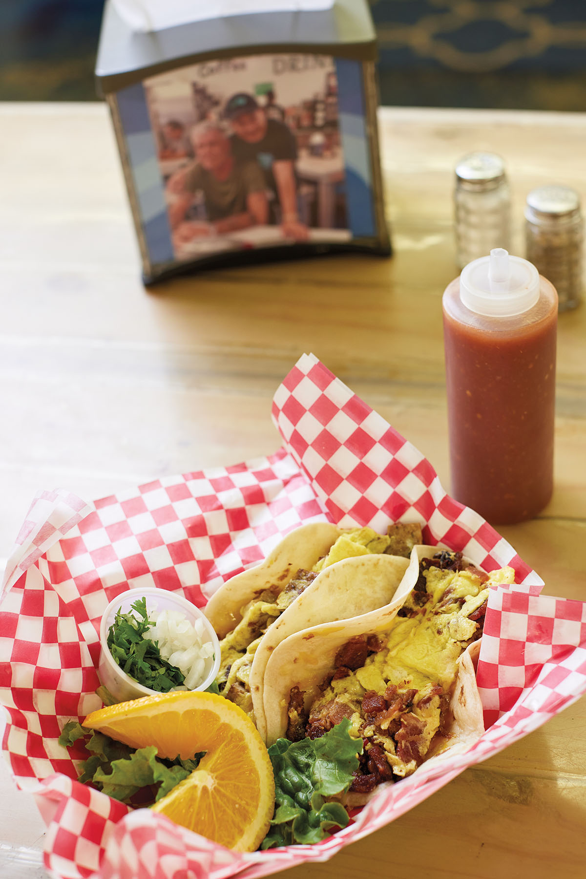 Breakfast tacos served in a basket lined with red and white checkered paper