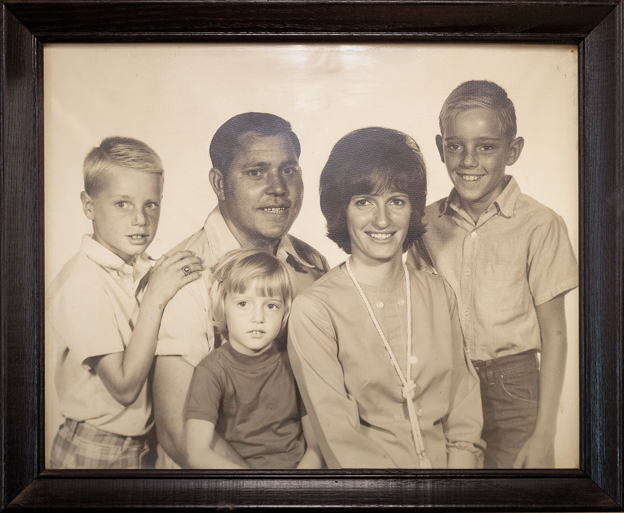 A sepia tone family portrait in a black frame