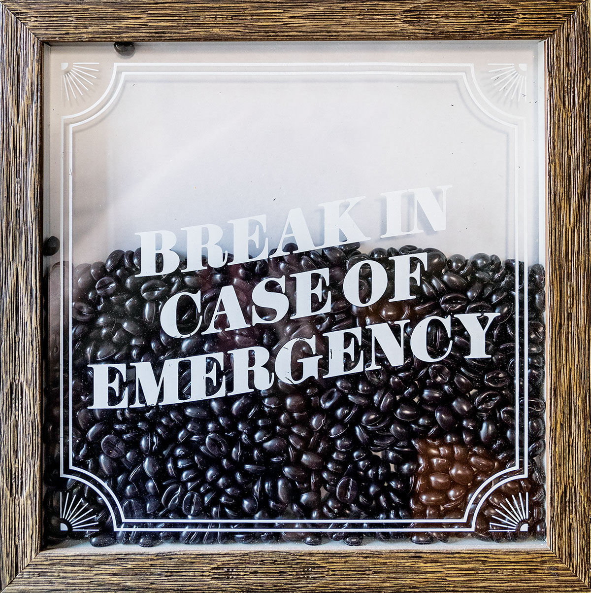 A glass box reading "Break in case of emergency" full of coffee beans