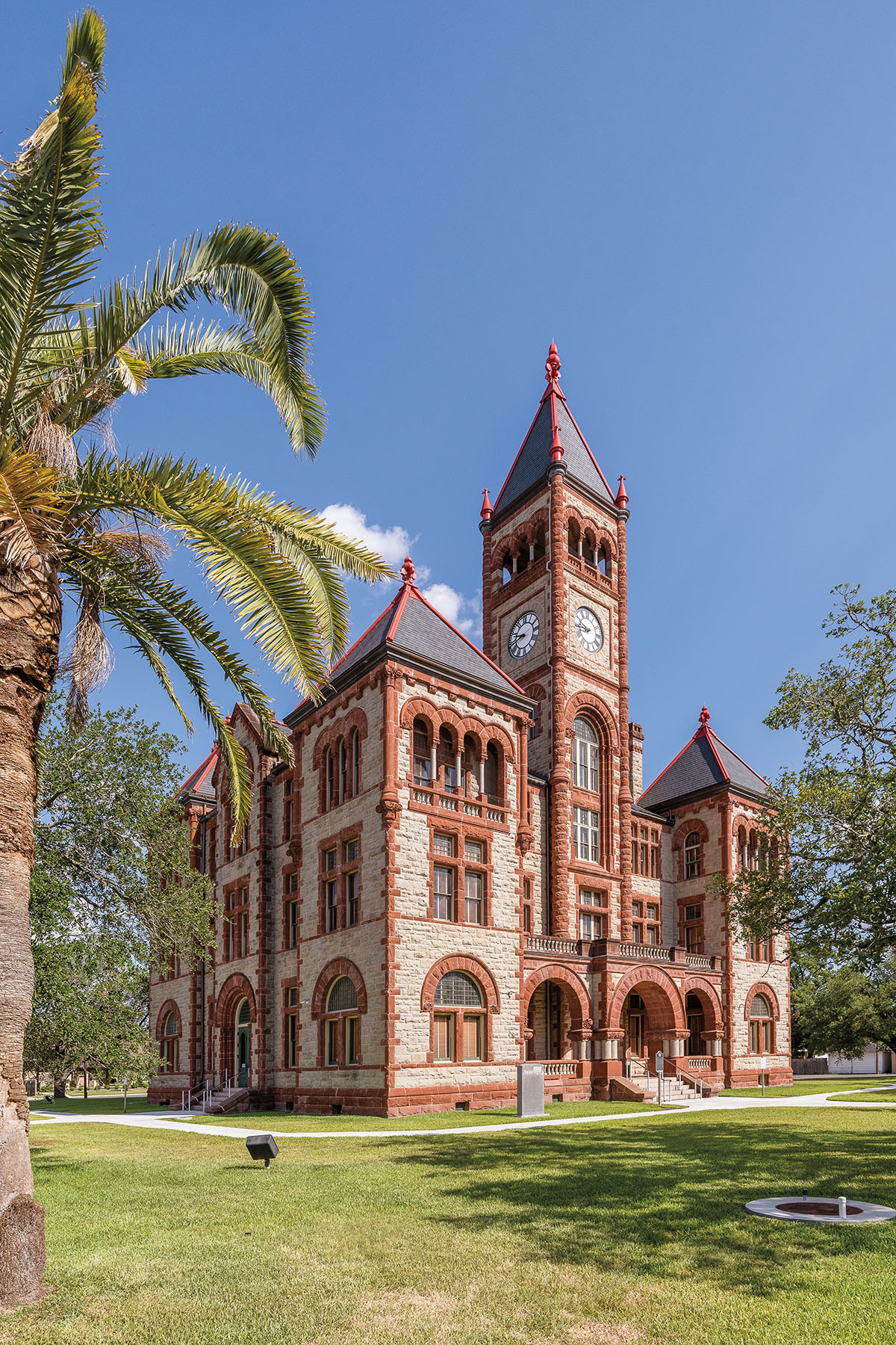 The exterior of an ornate courthouse with red brick stone accents under blue sky