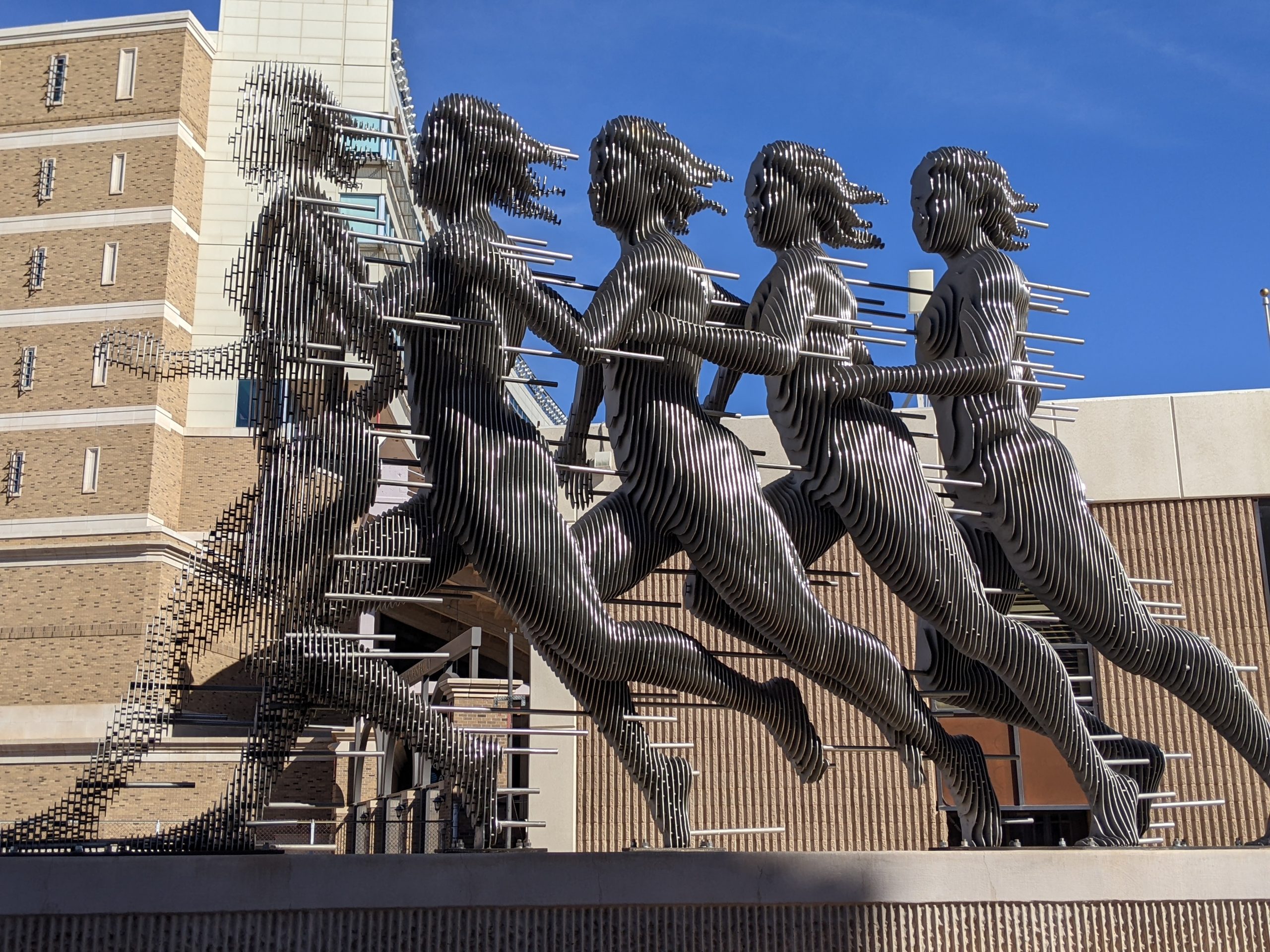 A sculpture made of metal depicts a woman running. It is located on the Texas Tech University campus