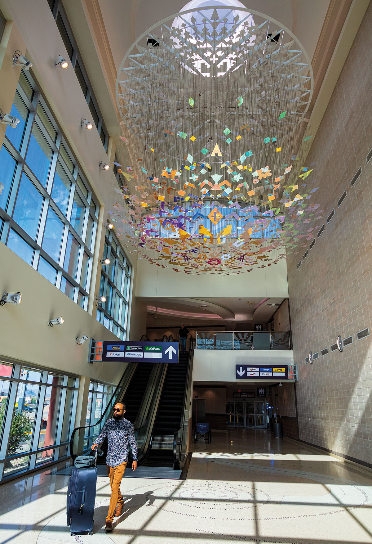 A brightly colored sculpture and mobile in front of large windows