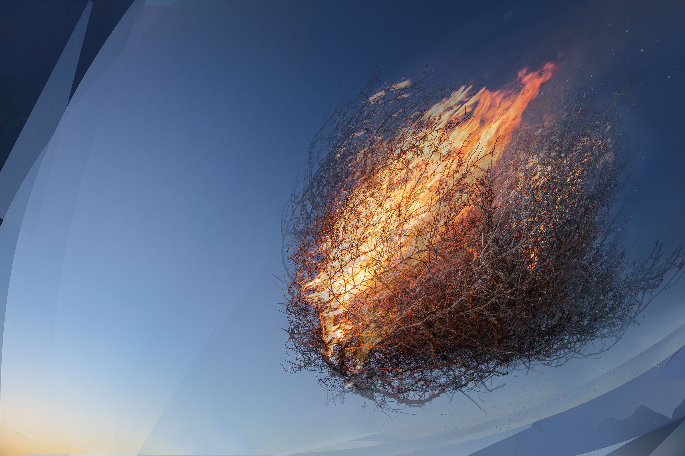 An image of a burning tumbleweed flying through the air on a dark blue night sky