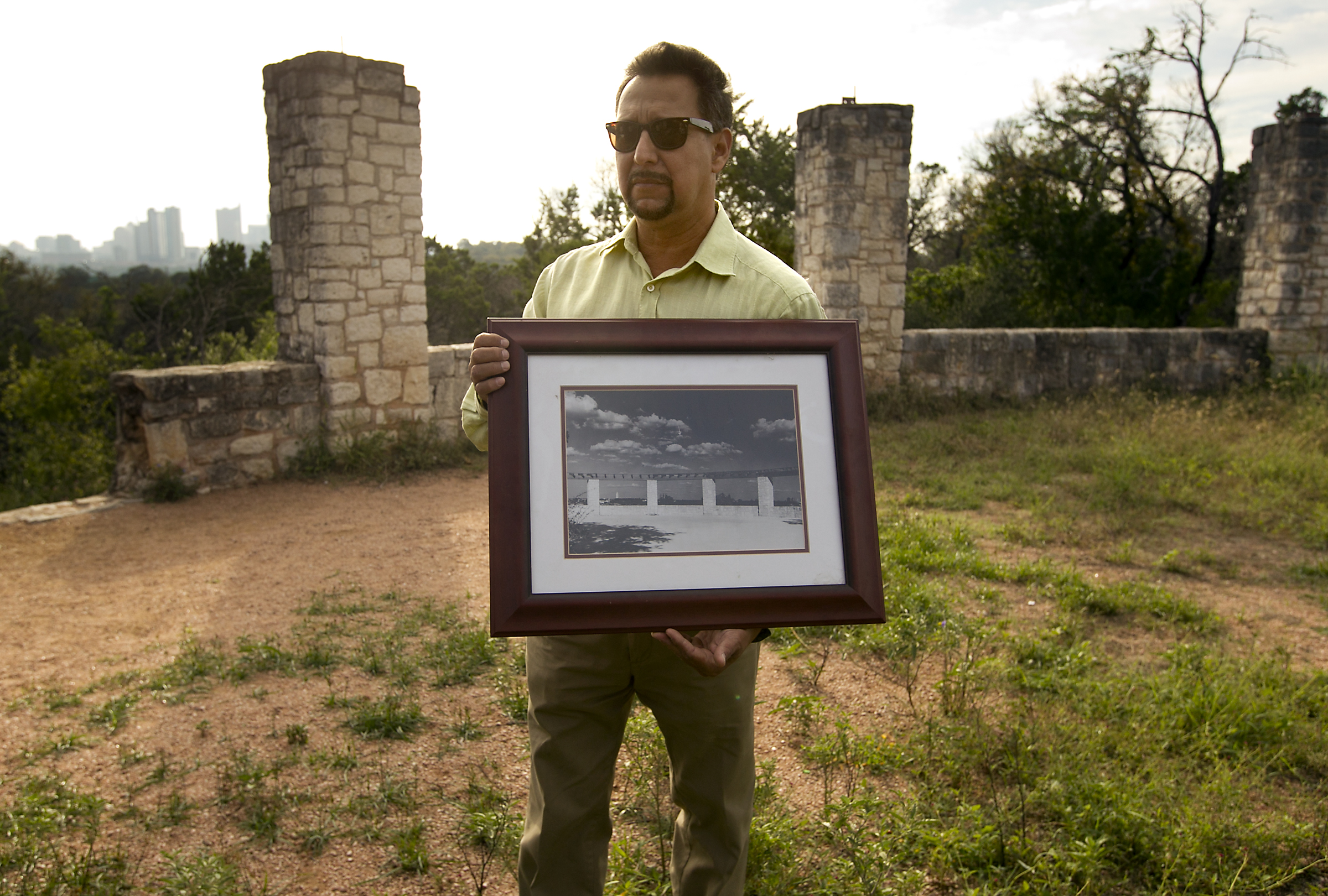 man in sunglasses holds a picture frame outside