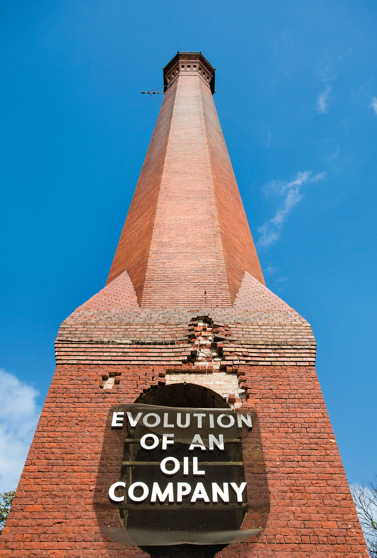 A tall brick smokestack with lettering on the front reading Evolution of an Oil Company