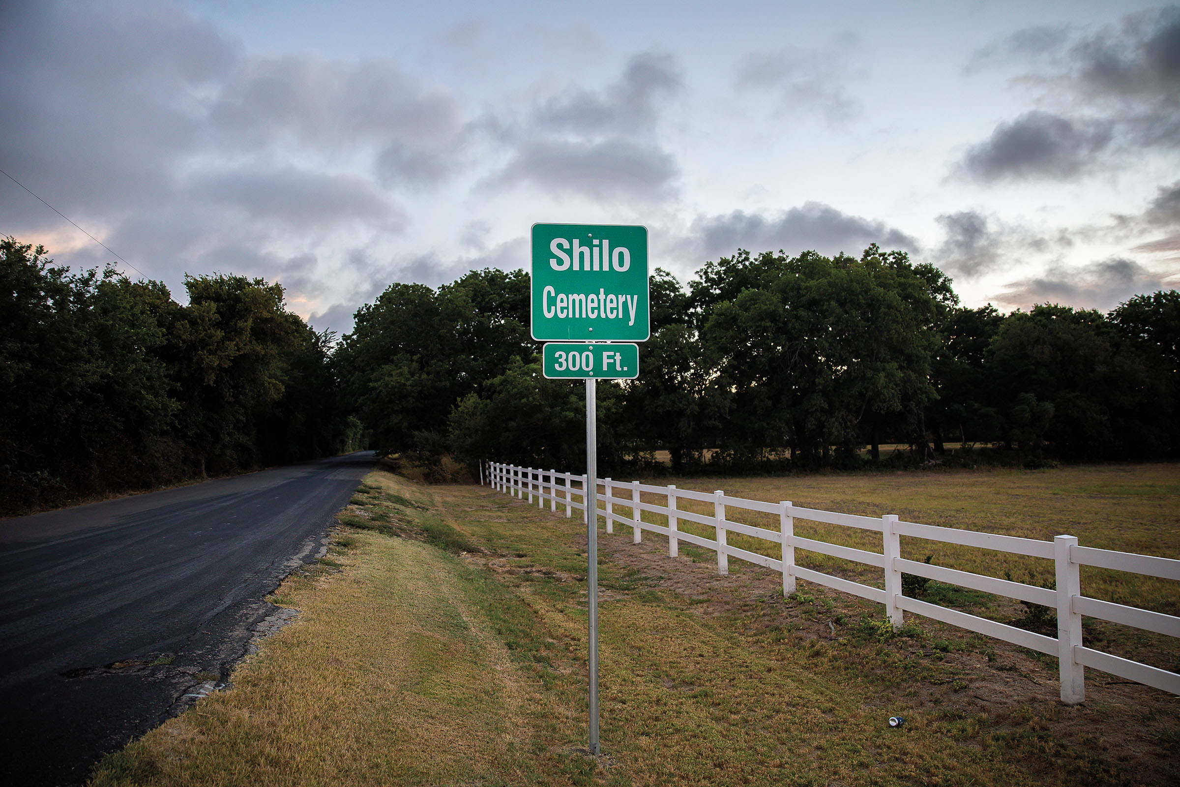 A green sign along a road reading "Shilo [sic] Cemetery"