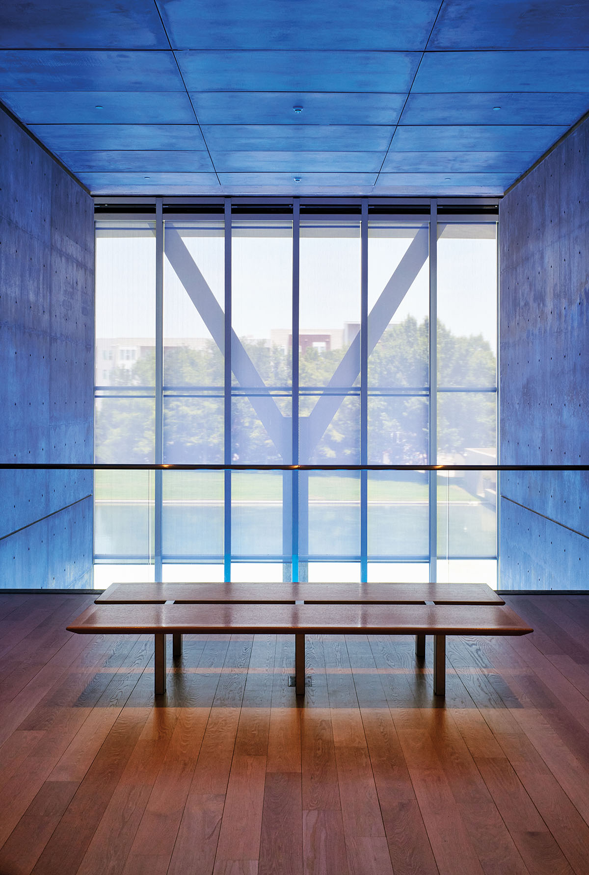 Light streams through window panes in a blue-painted room with wooden benches