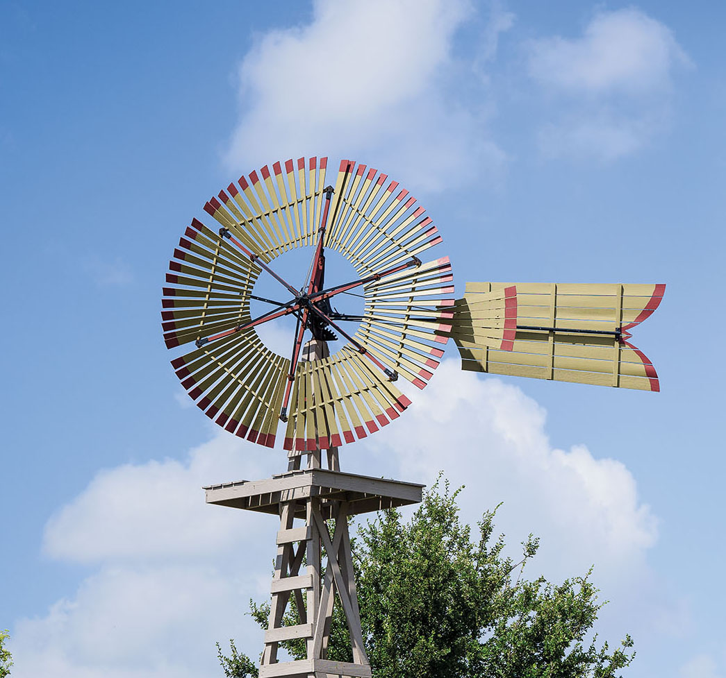 A windmill in front of a blue sky and cloud background