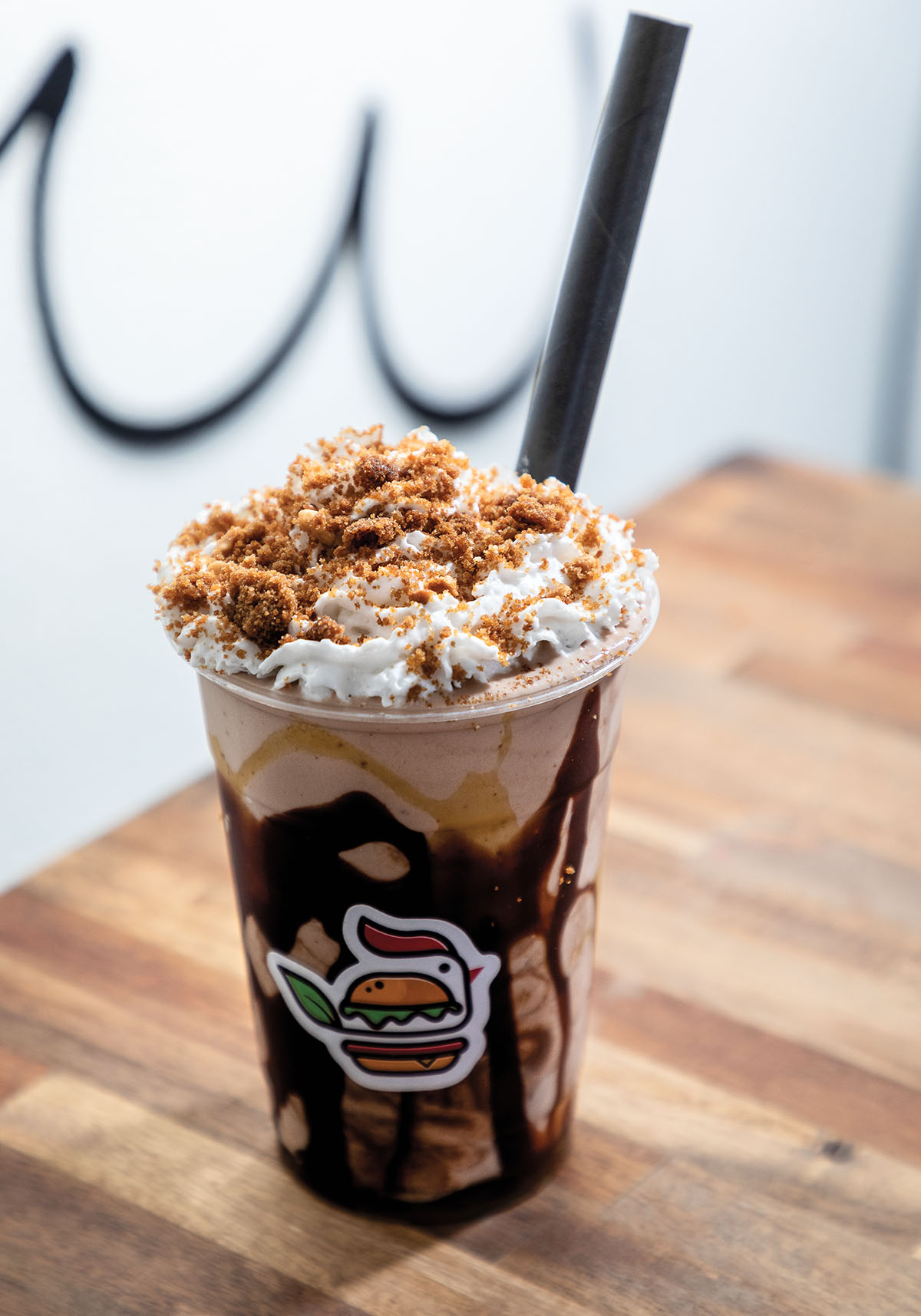A plastic cup filled with swirls of chocolate, chocoalte ice cream, and topped with whipped topping and cookie crumbles