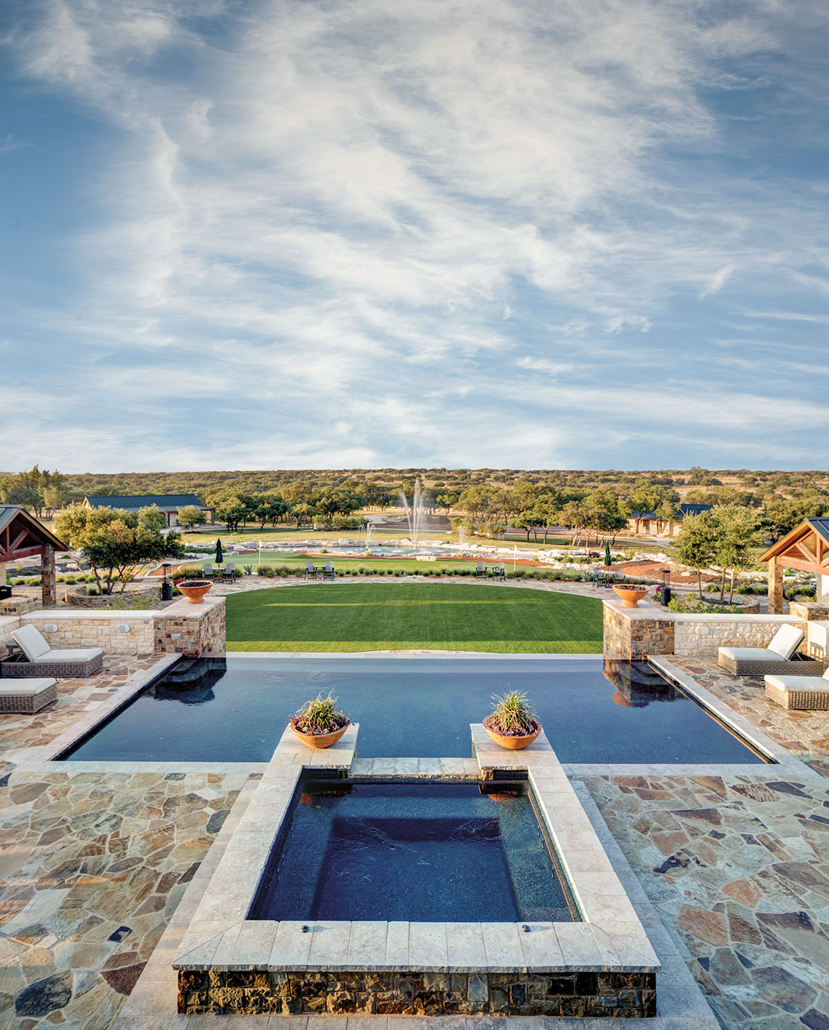 A glistening pool framed by light rock under a wide sky with clouds