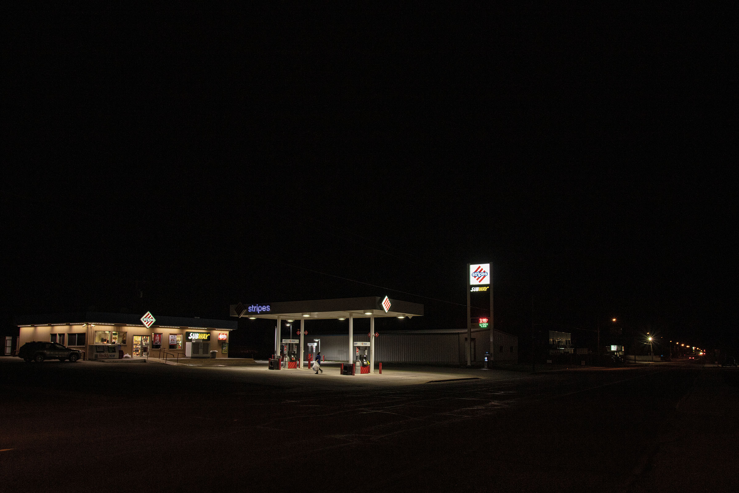 The exterior of a Stripes gas station, the only light around in this nighttime scene