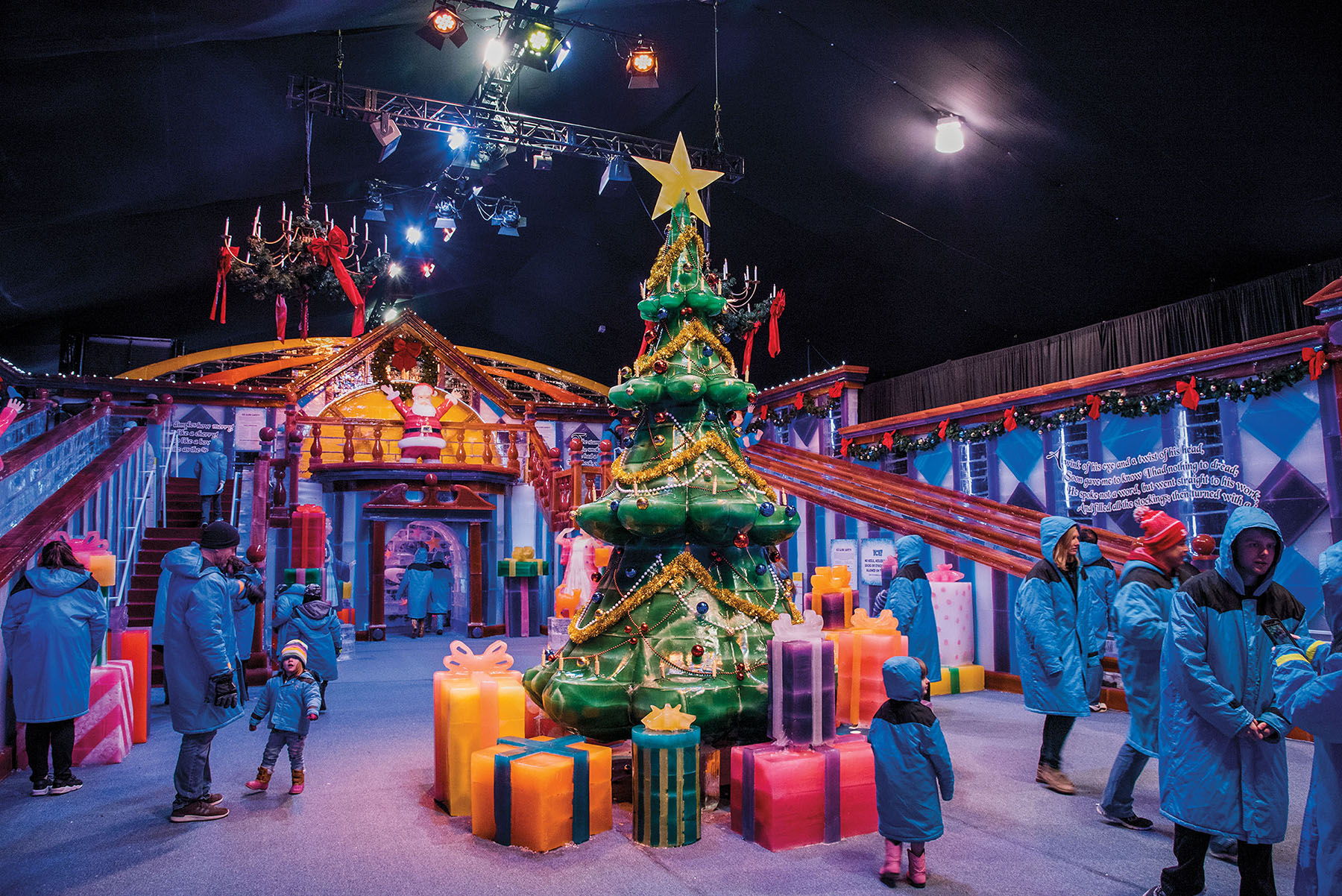 Ice sculptures of trees and presents inside of a large tent with lights