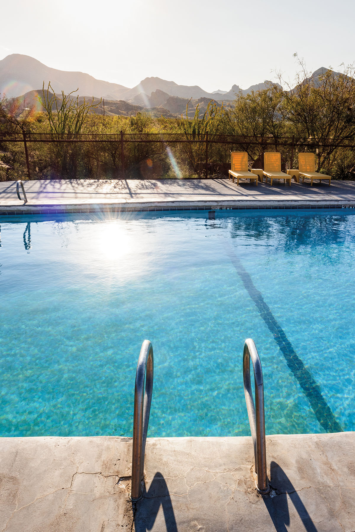 A glittering blue swimming pool in front of a backdrop of tall mountains