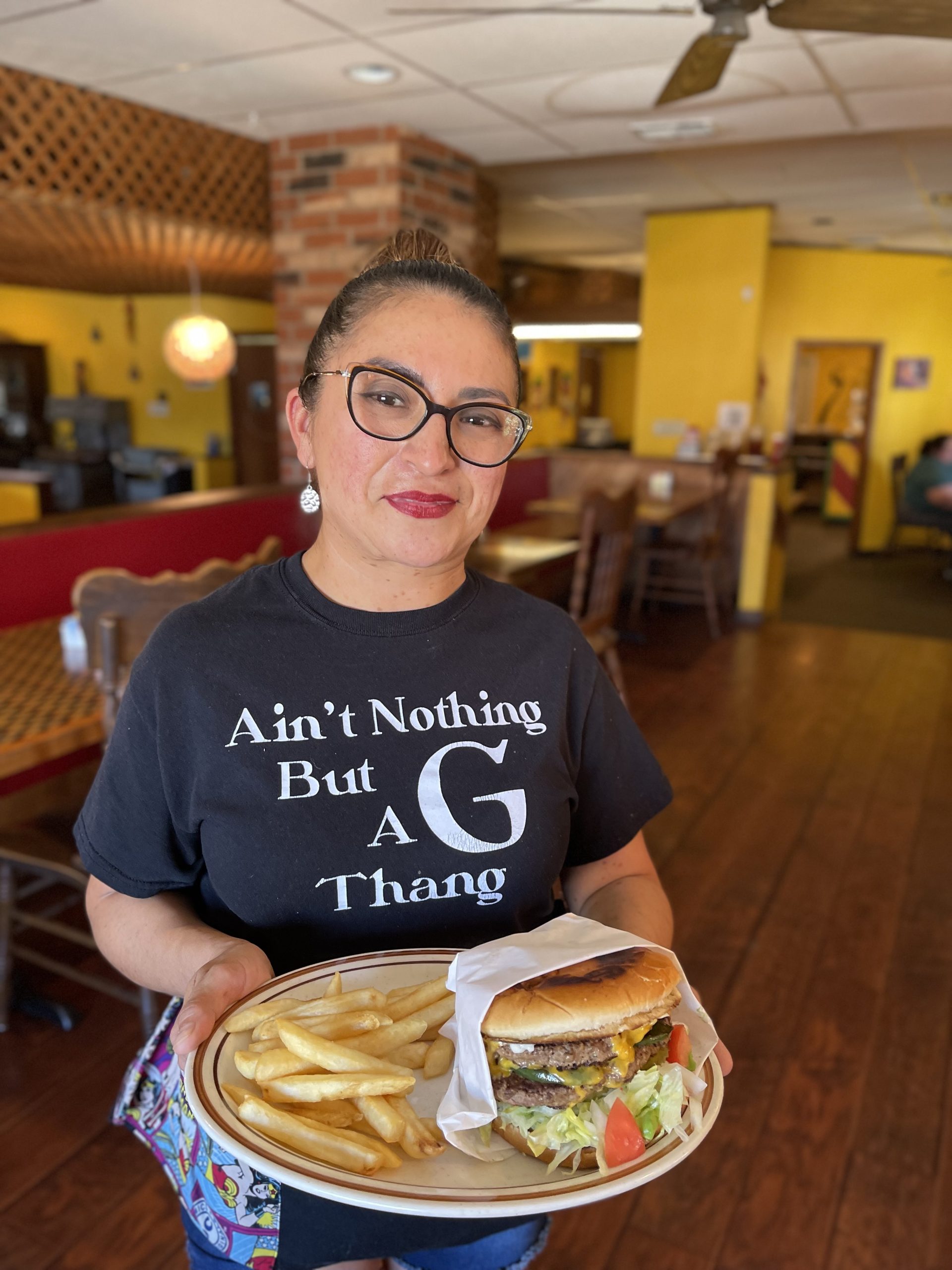 a woman in glasses with a burger and fries