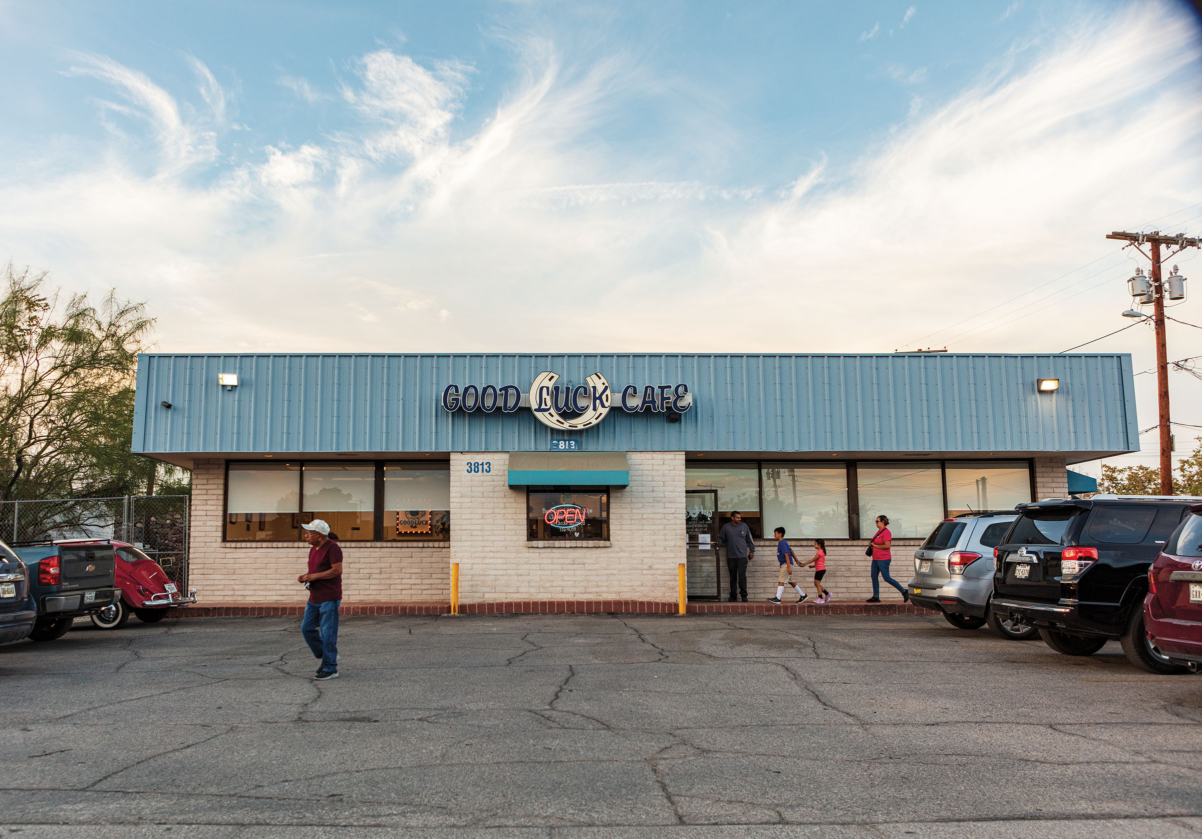 The exterior of a cafe with a blue roof under blue sky with a few clouds