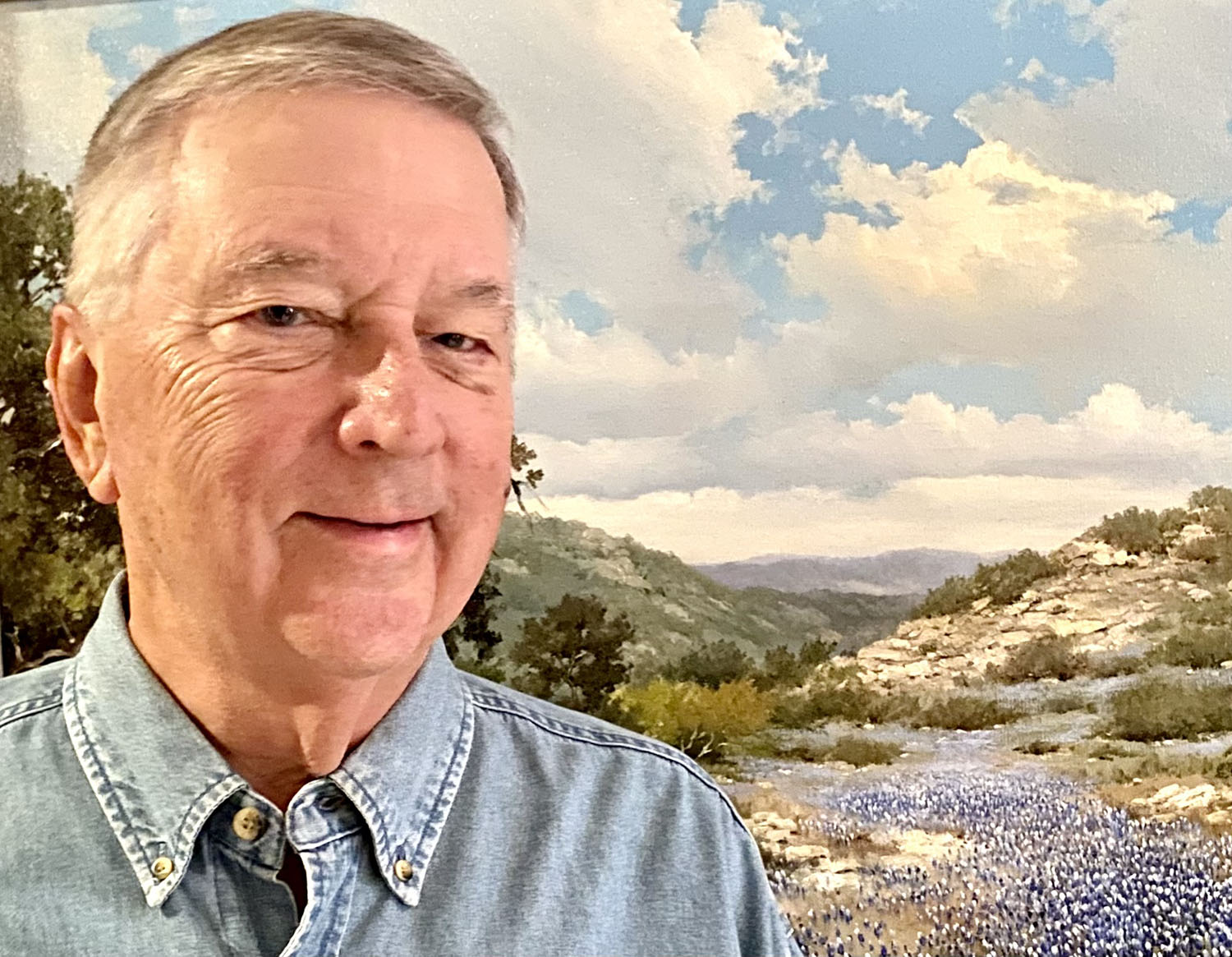 A picture of the author in front of a painting of bluebonnets