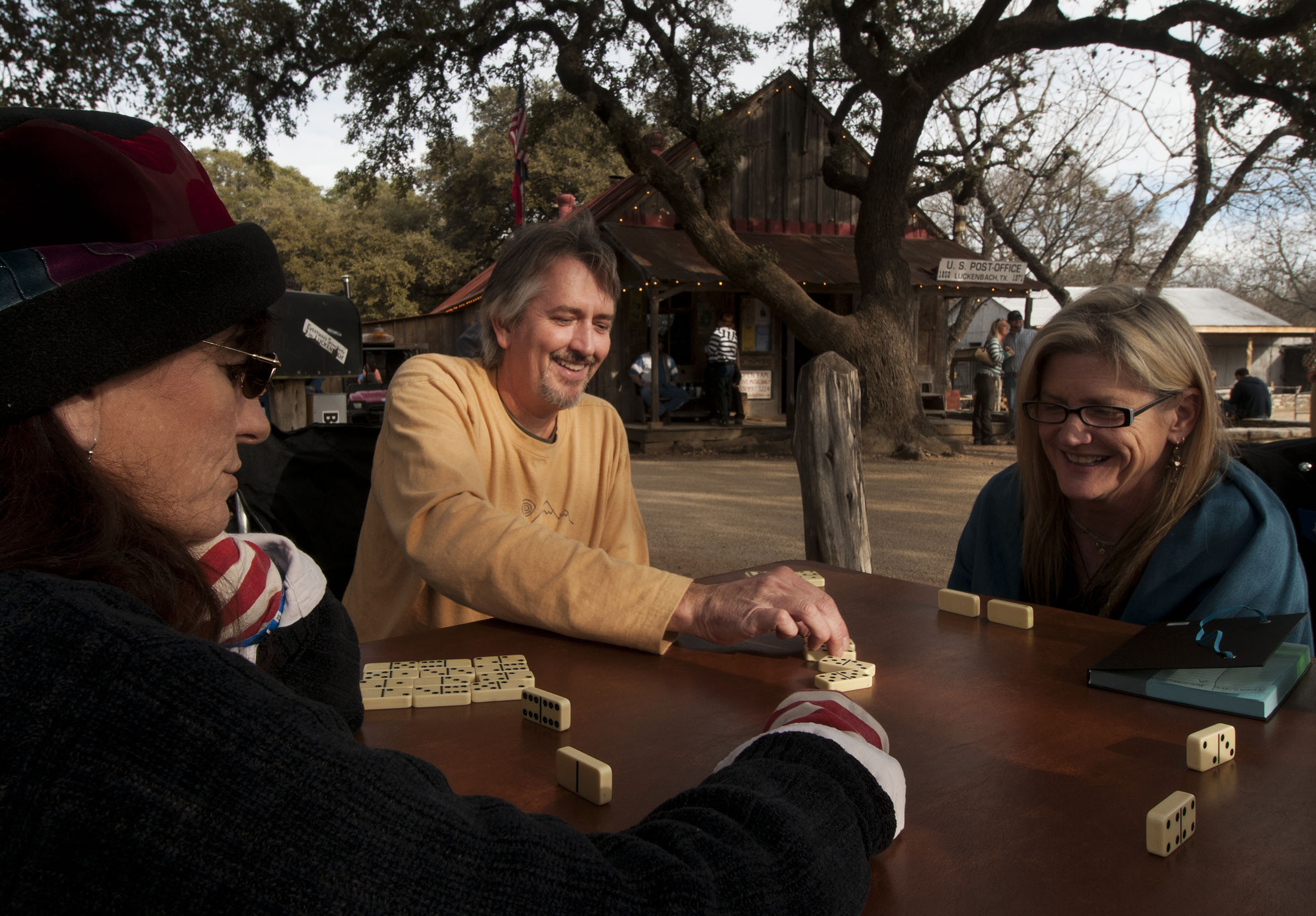 A group of people sit around a table playing dominoes