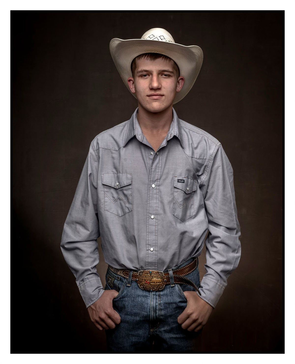A young man in a white cowboy hat poses with his hands in his pockets