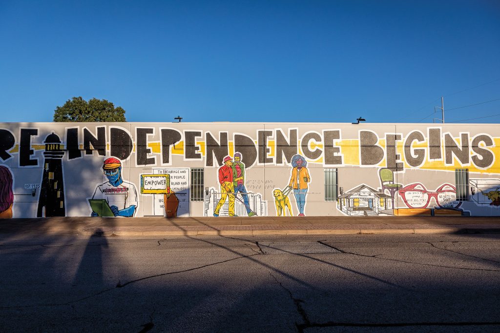A concrete mural reading "Independence Begins" with drawings of people on a gray concrete wall