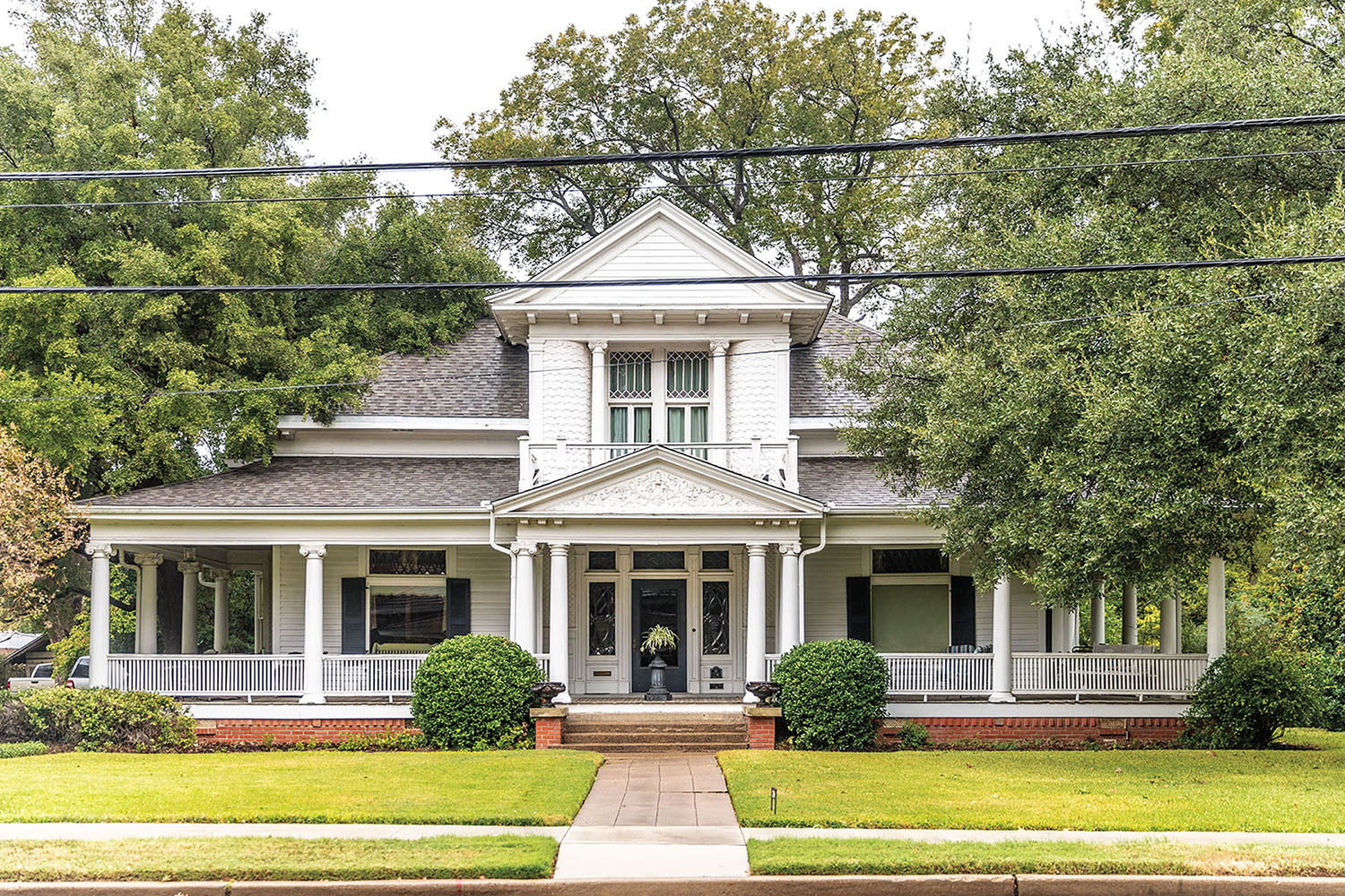 The exterior of a large historic Victorian-style home surrounded by green trees