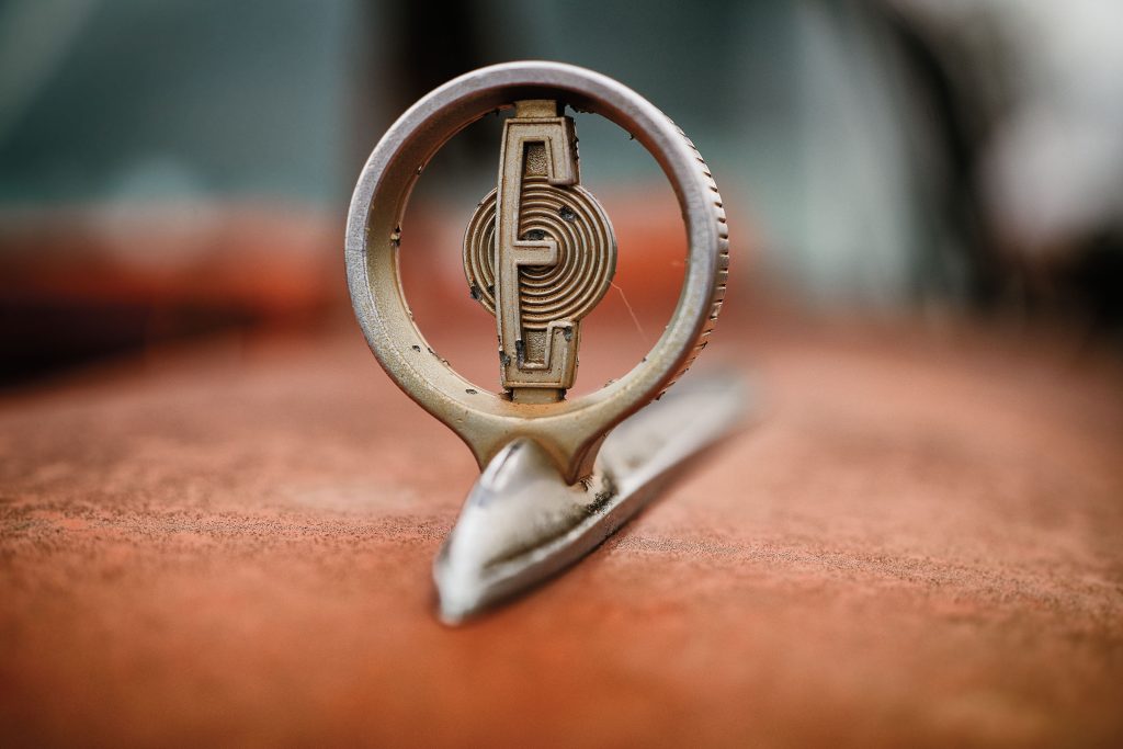 A hood ornament with a letter E inside of a metal circle