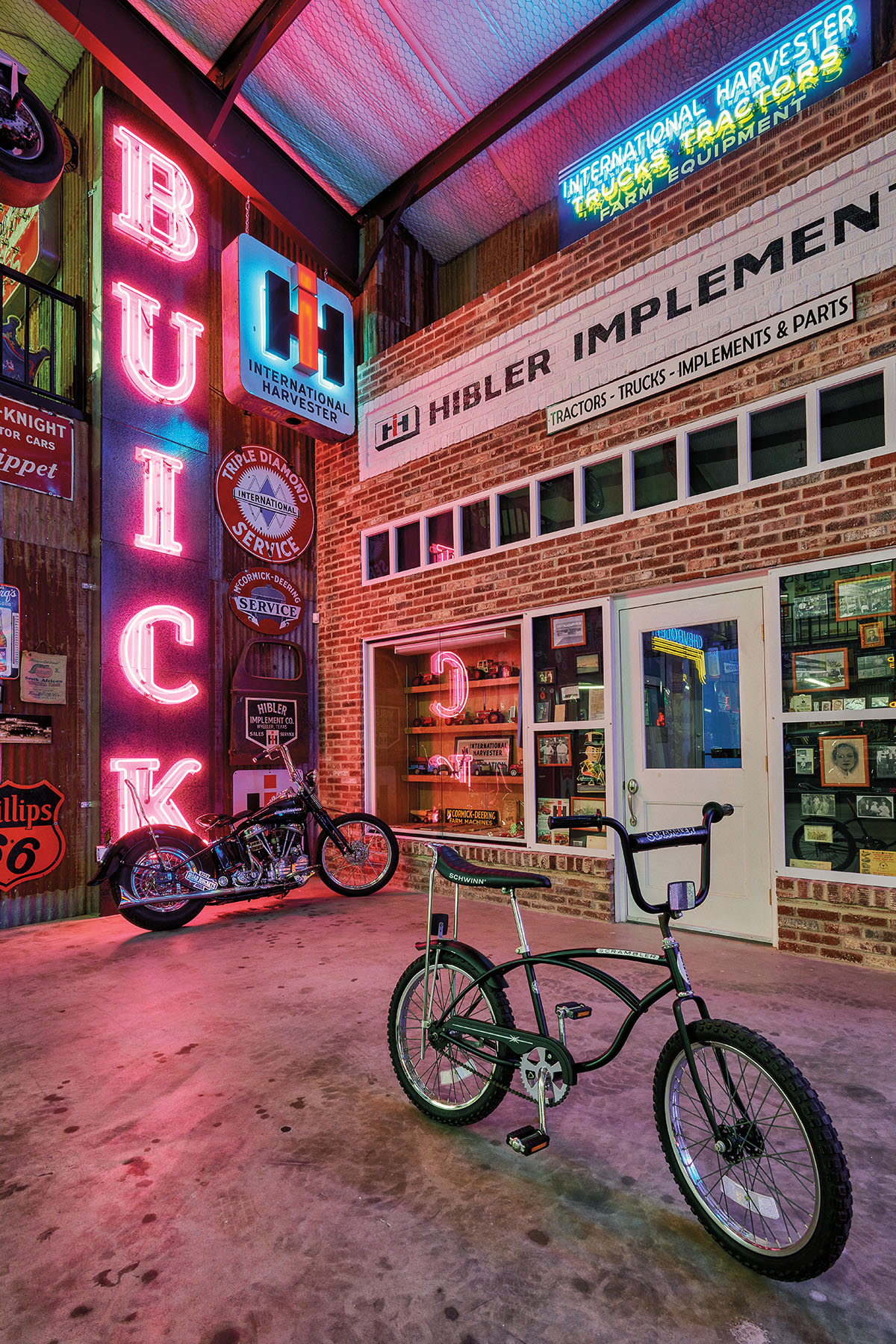 A small bicycle next to a motorcycle inside of a richly decorated auto showroom, with a neon sign reading "BUICK"