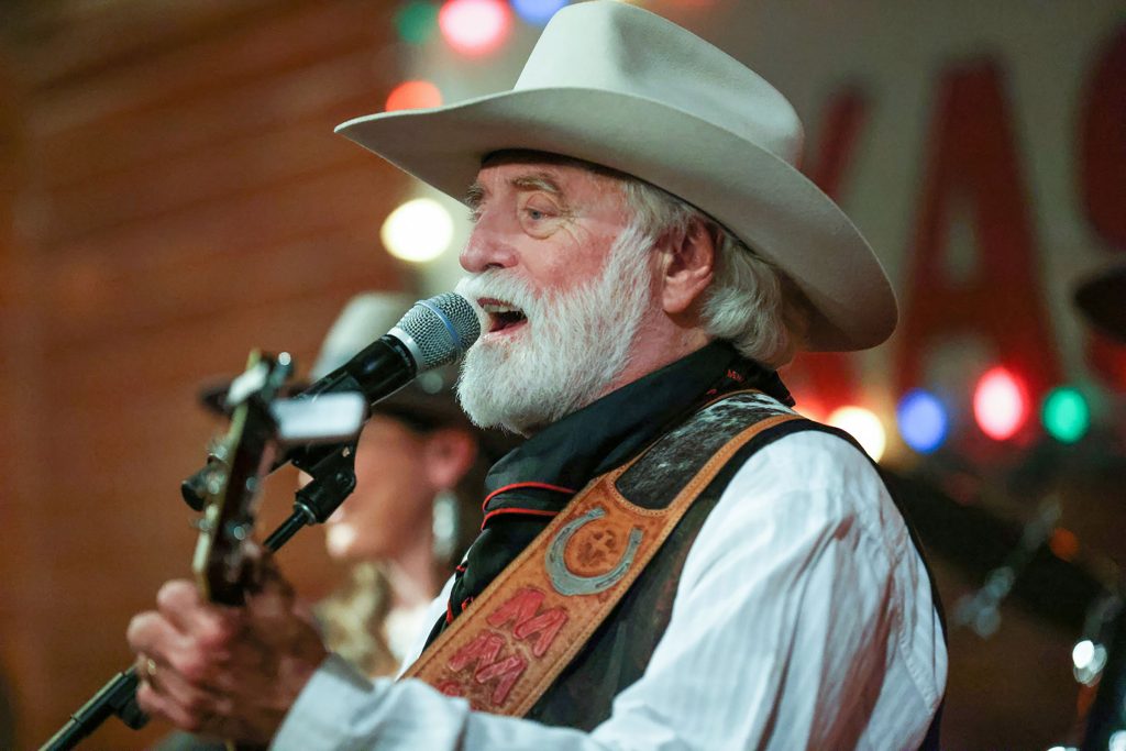 A man in a cowboy hat sings into a microphone