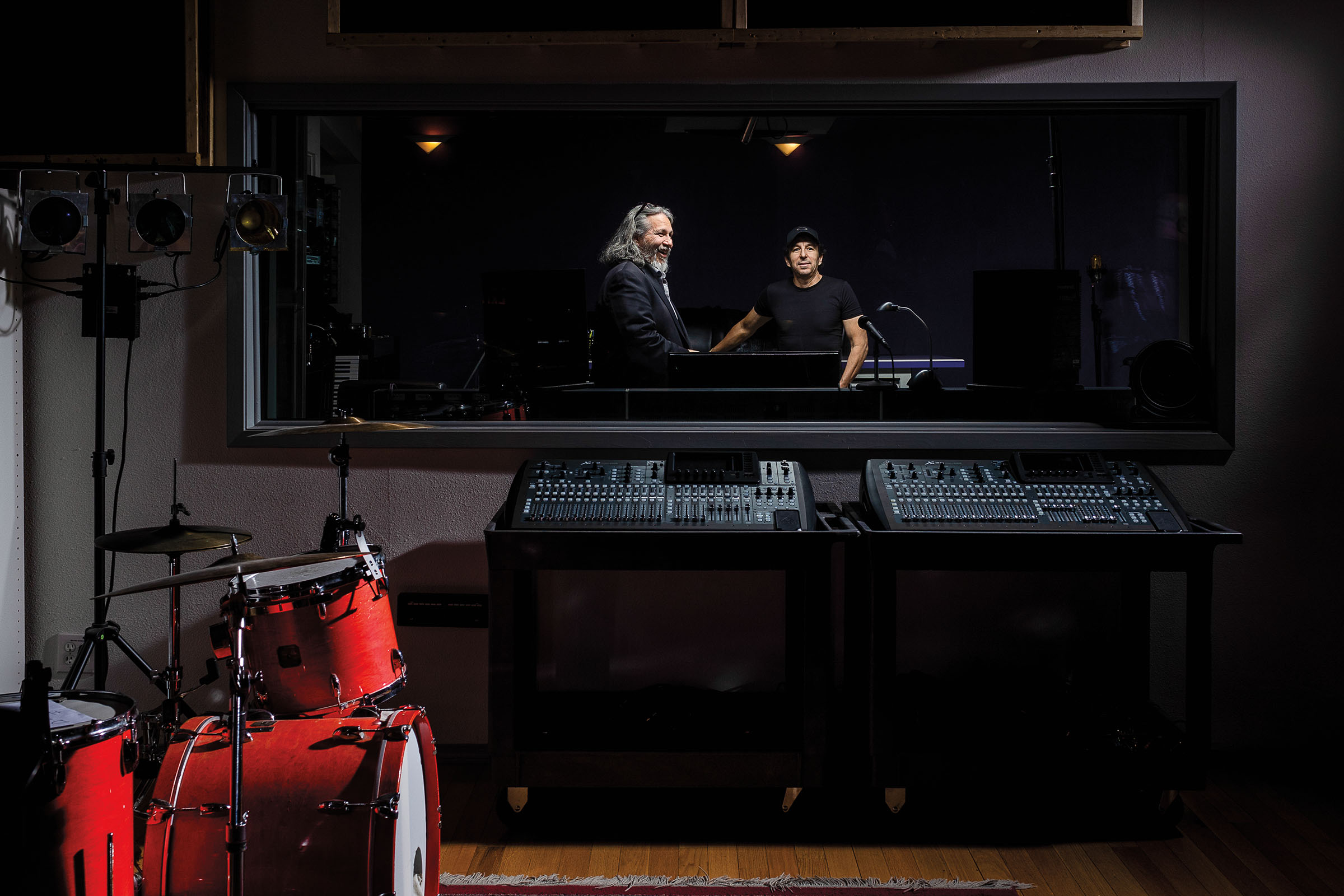 Two men stand in a dark recording studio