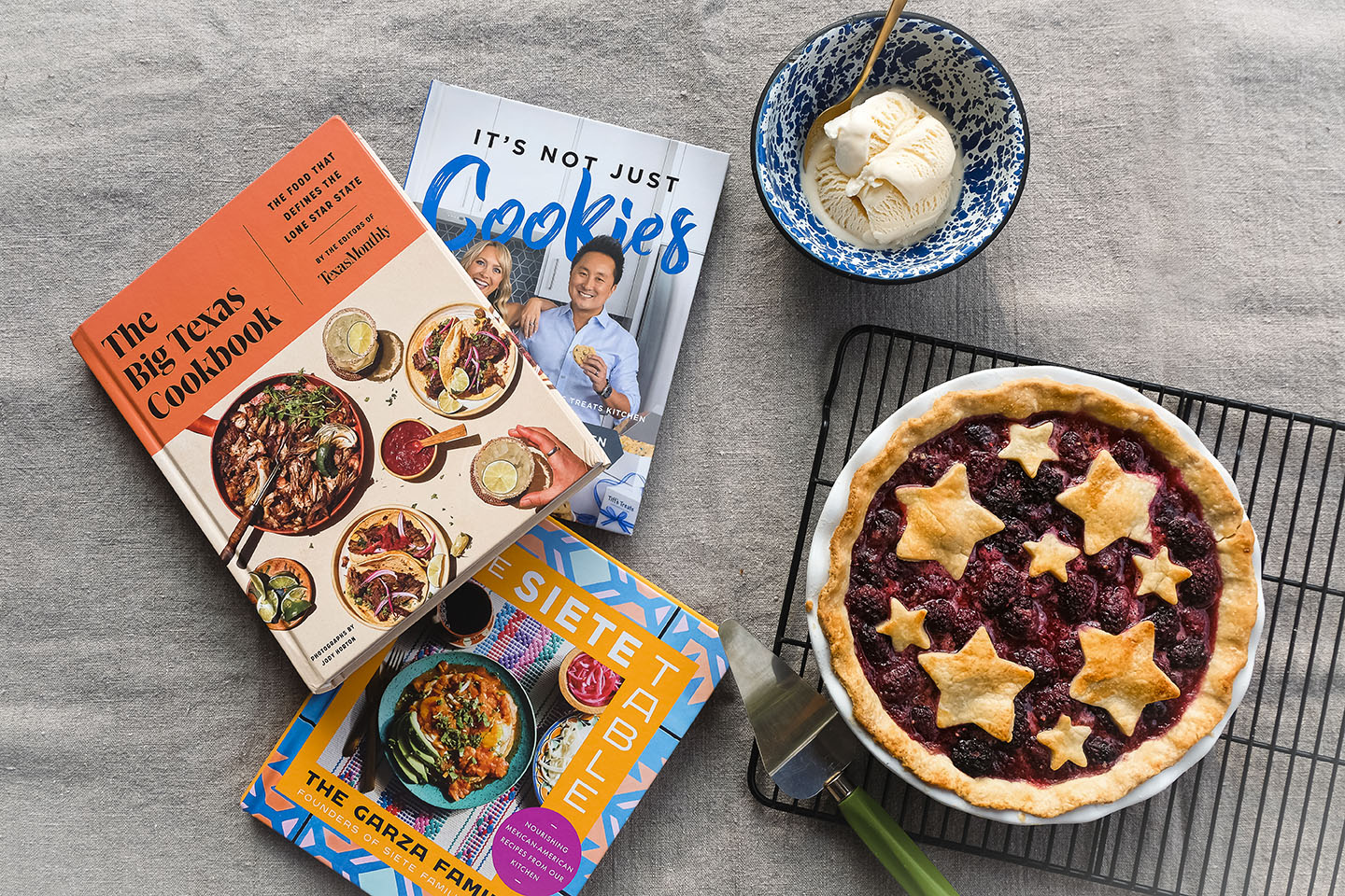 A collection of three Texas cookbooks with a fresh pie and bowl of ice cream on the side.