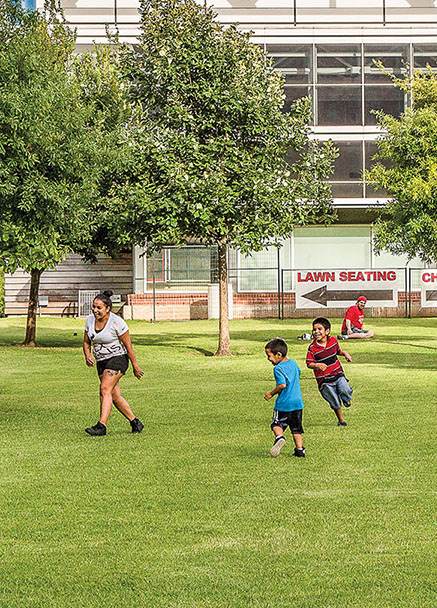 A group of people play soccer on a bright green field