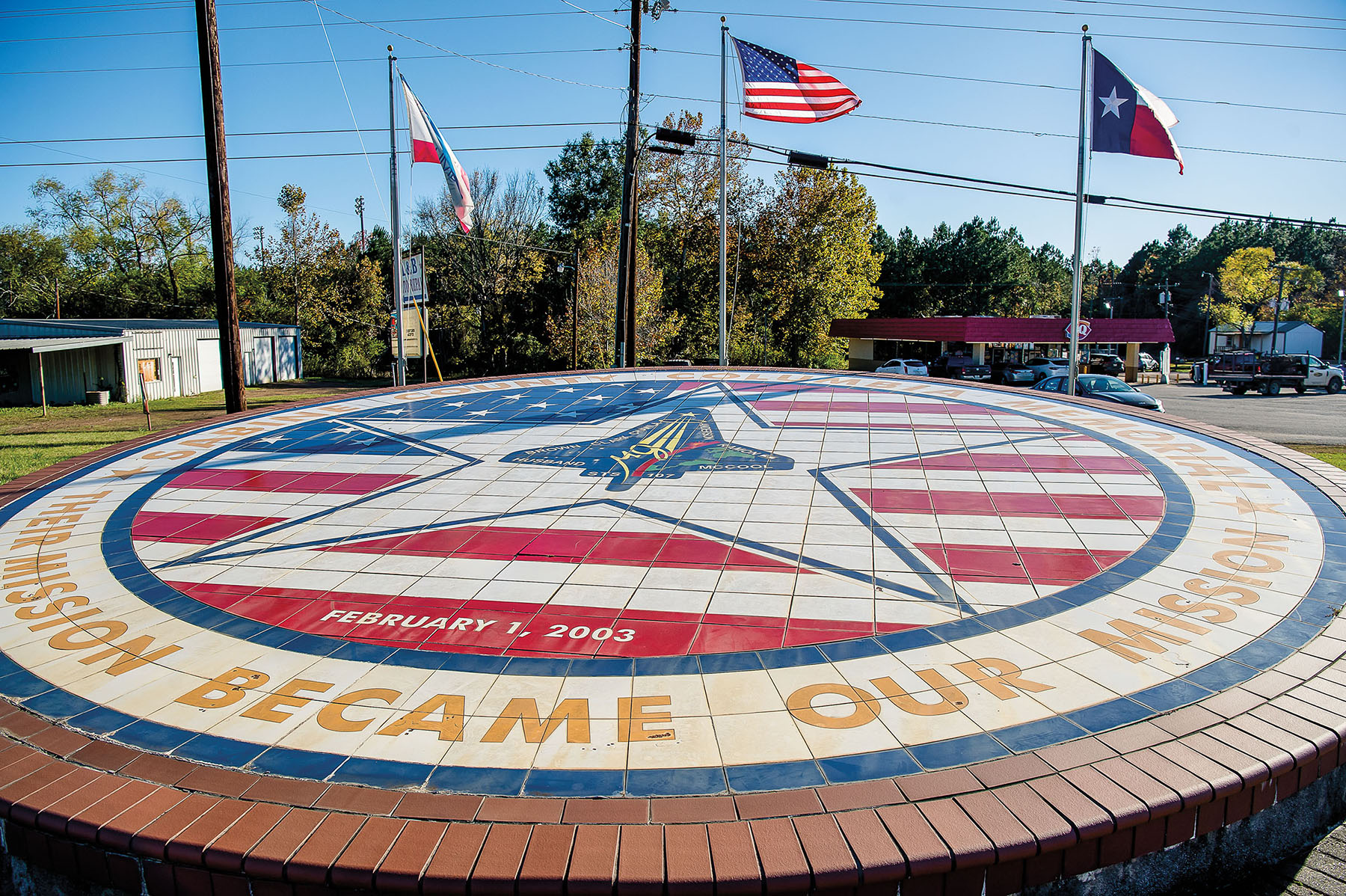 A red, white and blue circular collection of bricks under Texas and United States flags