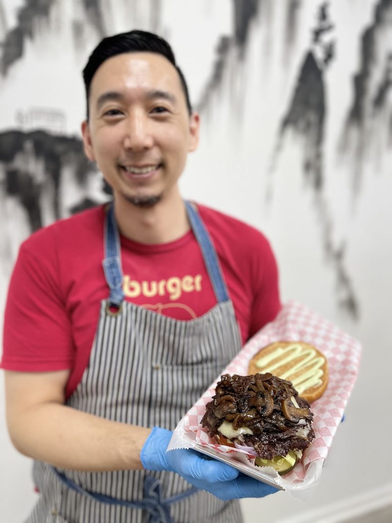 color photo of man holding open faced burger