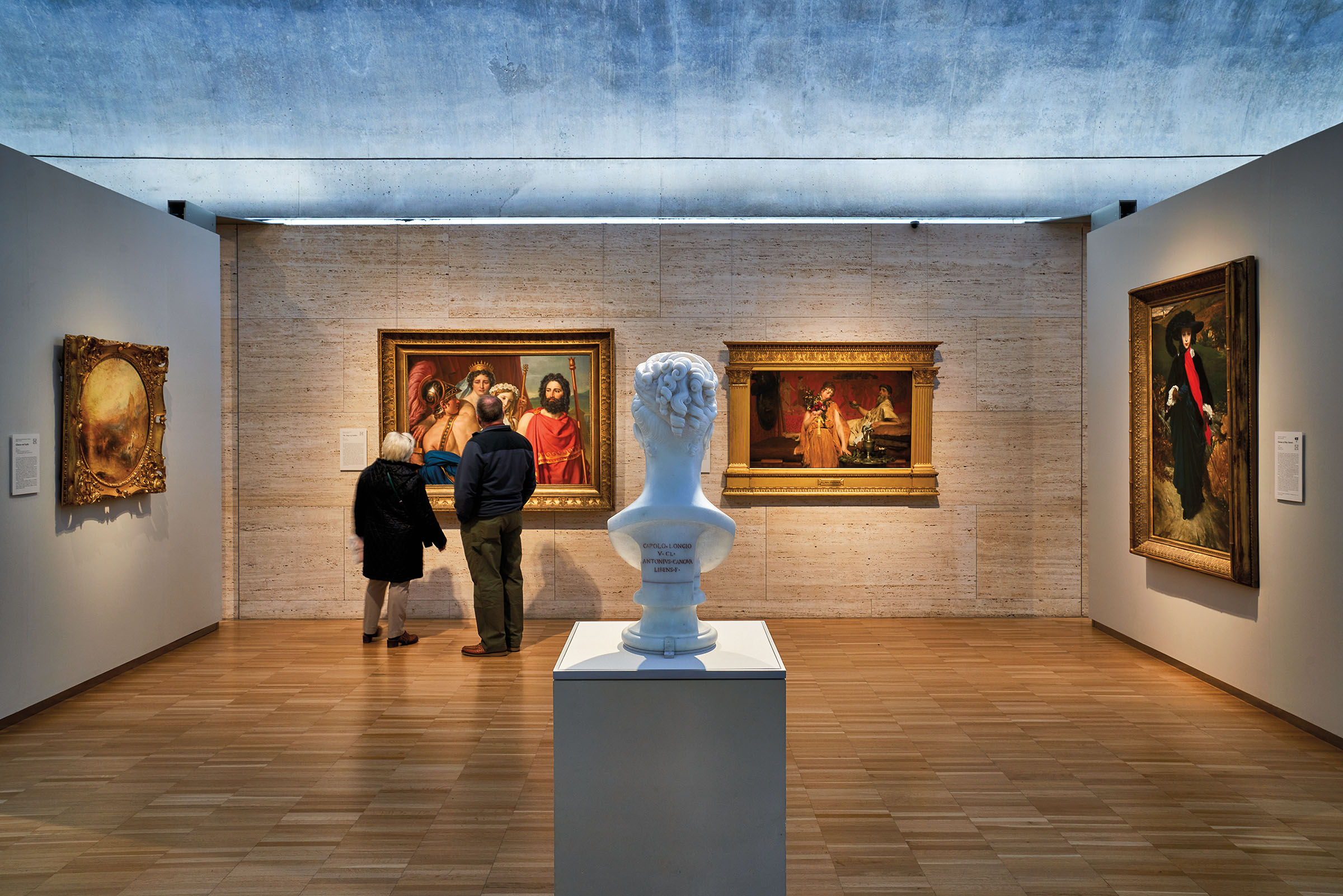 Two people admire a large painting on a gallery wall, behind a large sculpture