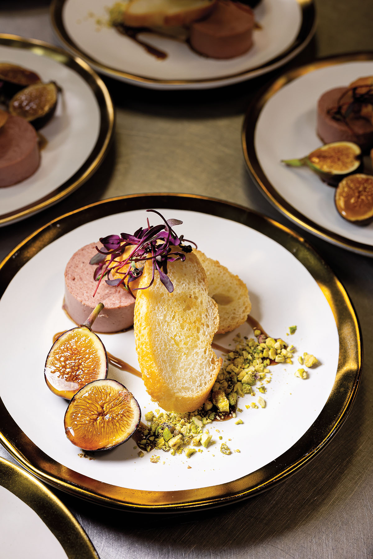A collection of carefully plated dishes including a pink patÃ© with charred fig on a white plate