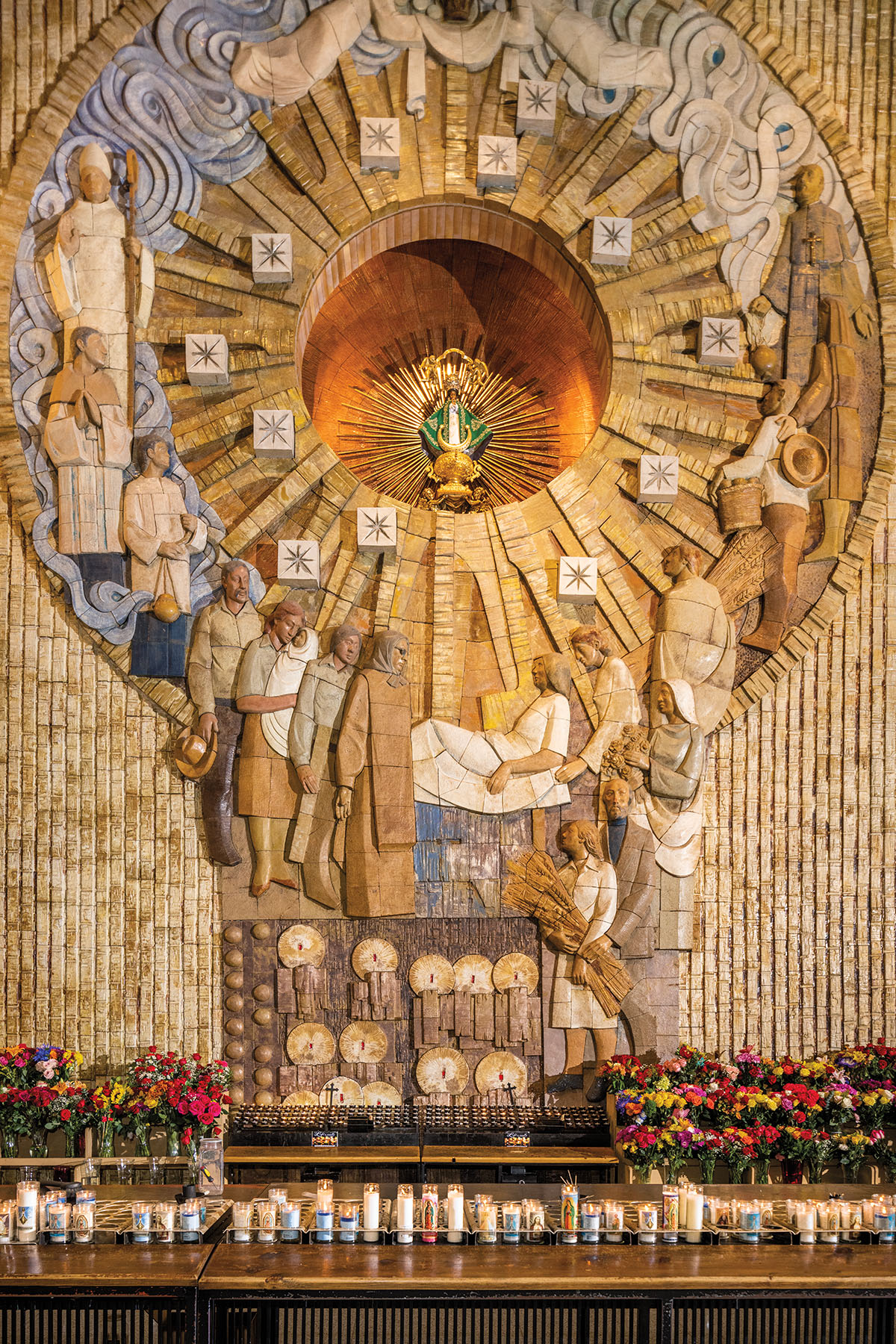 An incredibly ornate three-dimensional mural with a base of flowers and votive candles