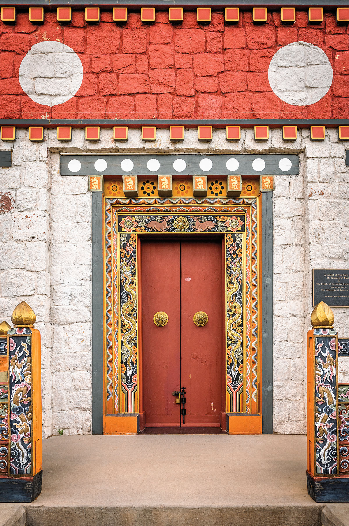 Ornately painted art surrounded two rust-colored red doors with large gold fixtures