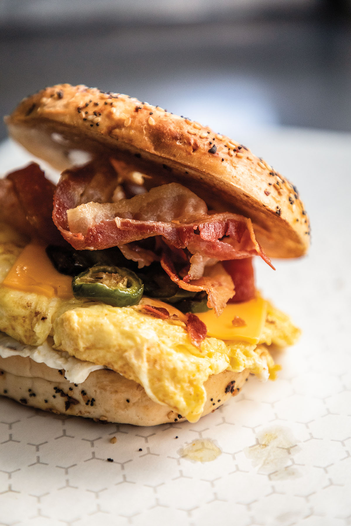 A toasted everything bagel piled high with bacon, jalapeÃ±os, egg, and cheese