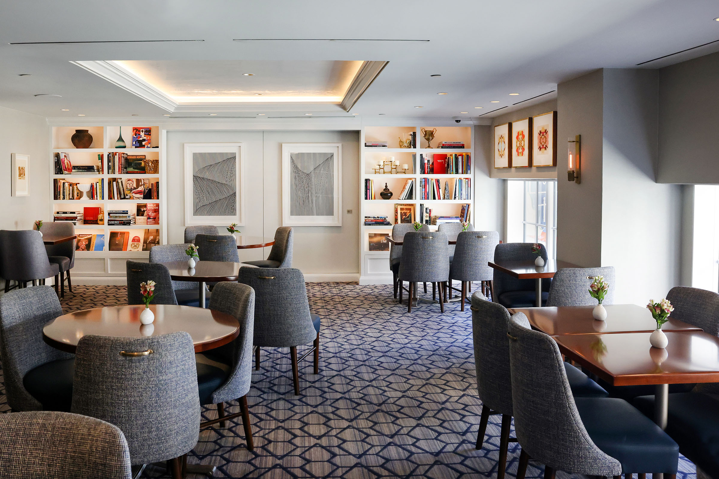 Colorful artwork and artifacts line white bookshelves in the hotel's dining area