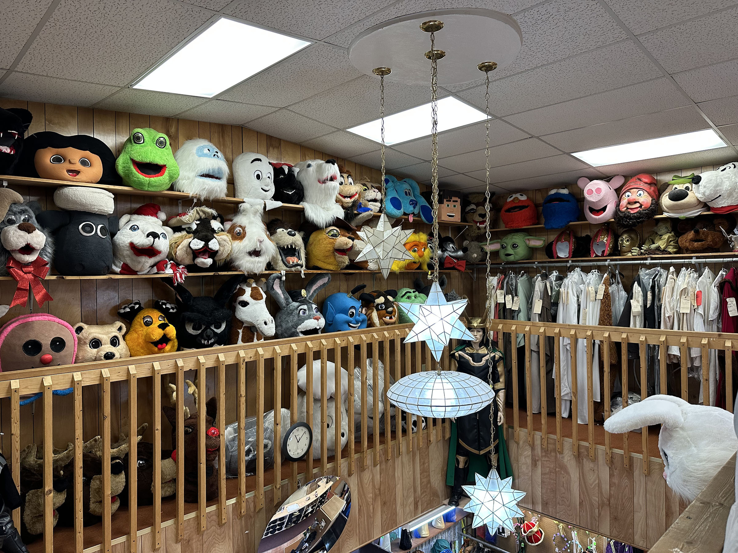 Shelves are lined with the heads of different mascots and monsters along an upstairs wall in the shop. Three pendant lights, two shaped like stars, the other an orb, hang from the ceiling.