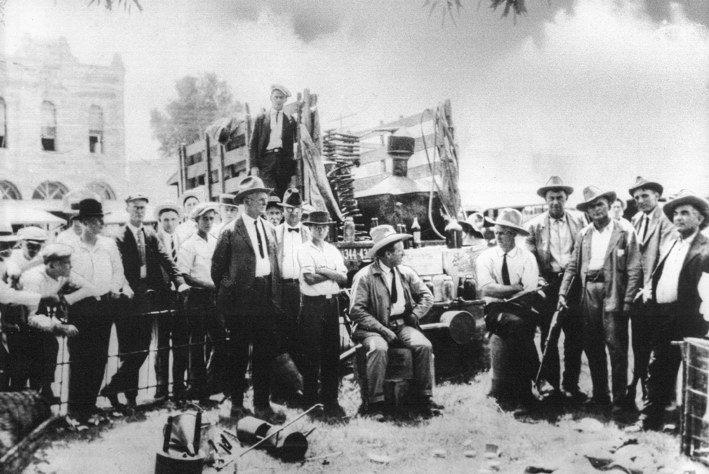 A black and white image of men standing around a truck filled with confiscated stills. 