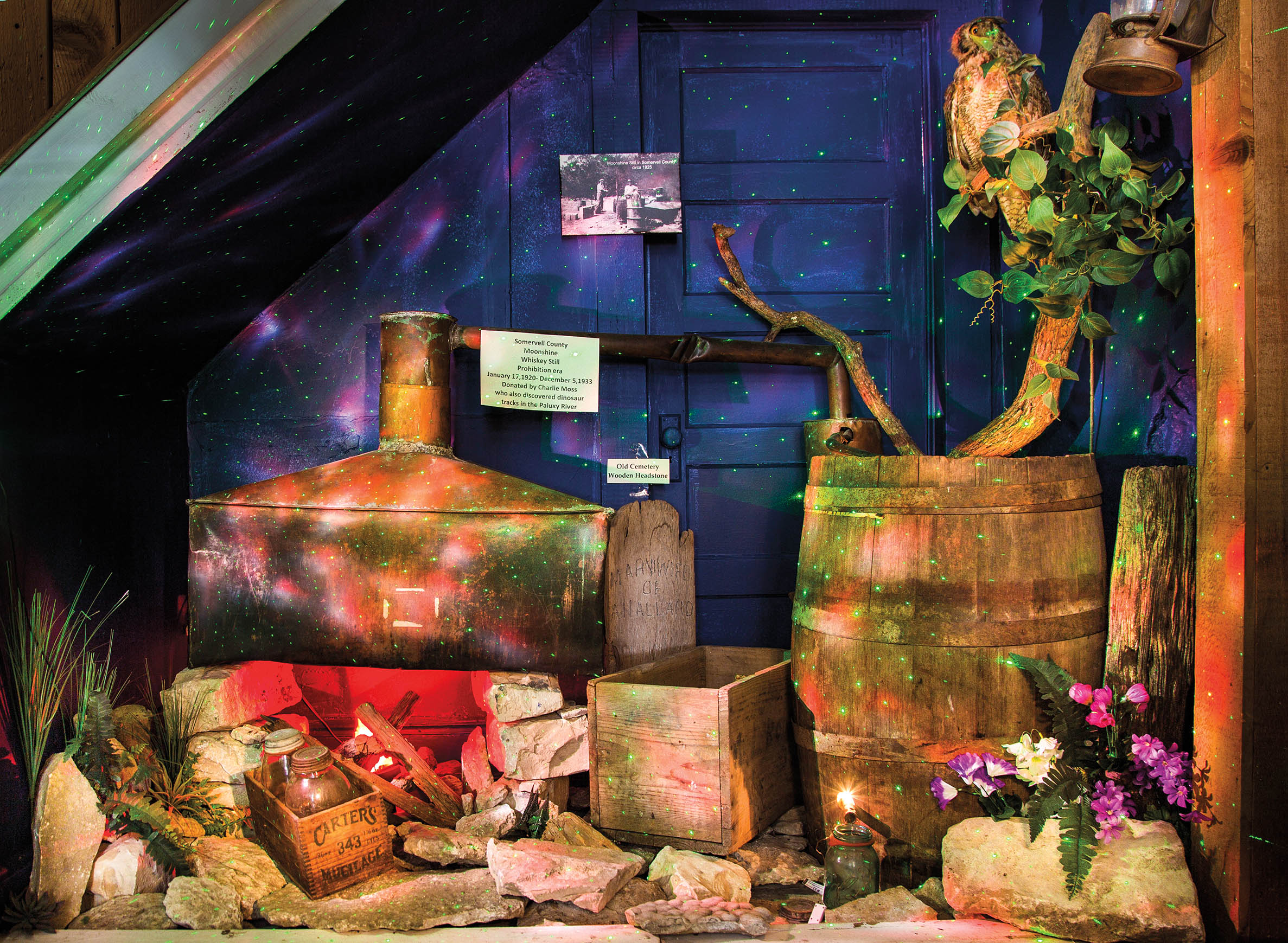 A display of a whiskey still, barrel, jars and more at a museum that is meant to recall the Prohibition era.